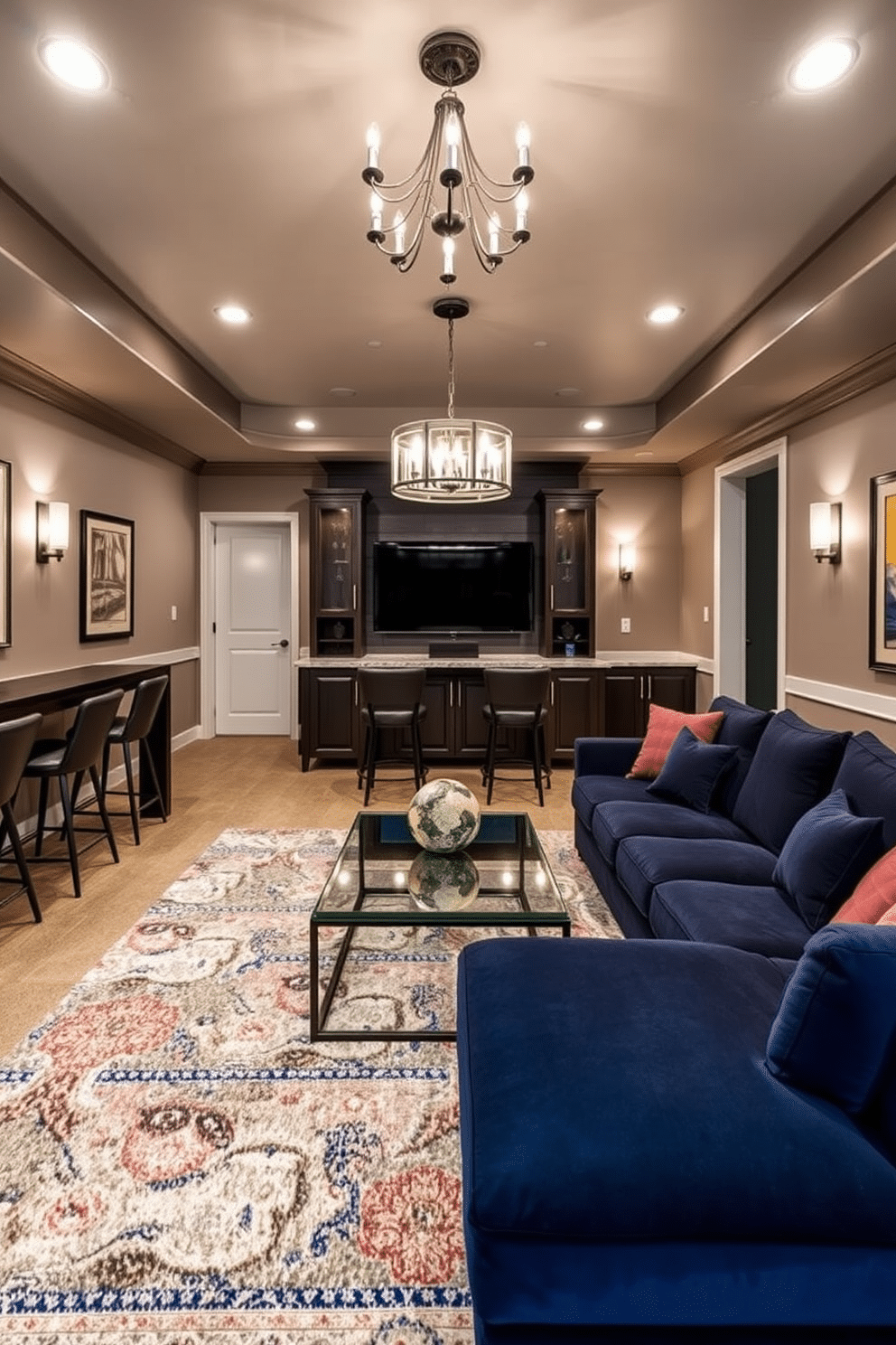 A stylish basement game room designed for entertainment and relaxation. The space features a large sectional sofa in a deep navy blue, paired with a sleek glass coffee table at the center. A statement chandelier hangs from the ceiling, casting a warm glow over the area. Wall-mounted sconces provide additional lighting, creating an inviting atmosphere for game nights. The walls are adorned with framed artwork and a mounted TV for gaming and movie viewing. A custom-built bar with high stools adds a touch of luxury, while a plush area rug defines the seating area.