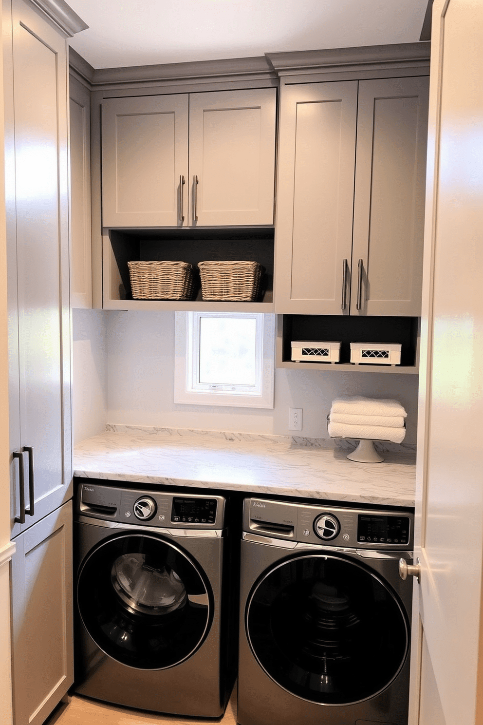 A modern basement laundry room features hidden appliances seamlessly integrated behind sleek cabinet doors, creating a clean and organized look. The cabinetry is finished in a soft gray tone, complementing the light-colored walls and enhancing the spacious feel of the room. Natural light filters in through a small window, illuminating a stylish countertop that provides ample space for folding laundry. Decorative baskets are neatly arranged on shelves, adding a touch of warmth and functionality to the space.