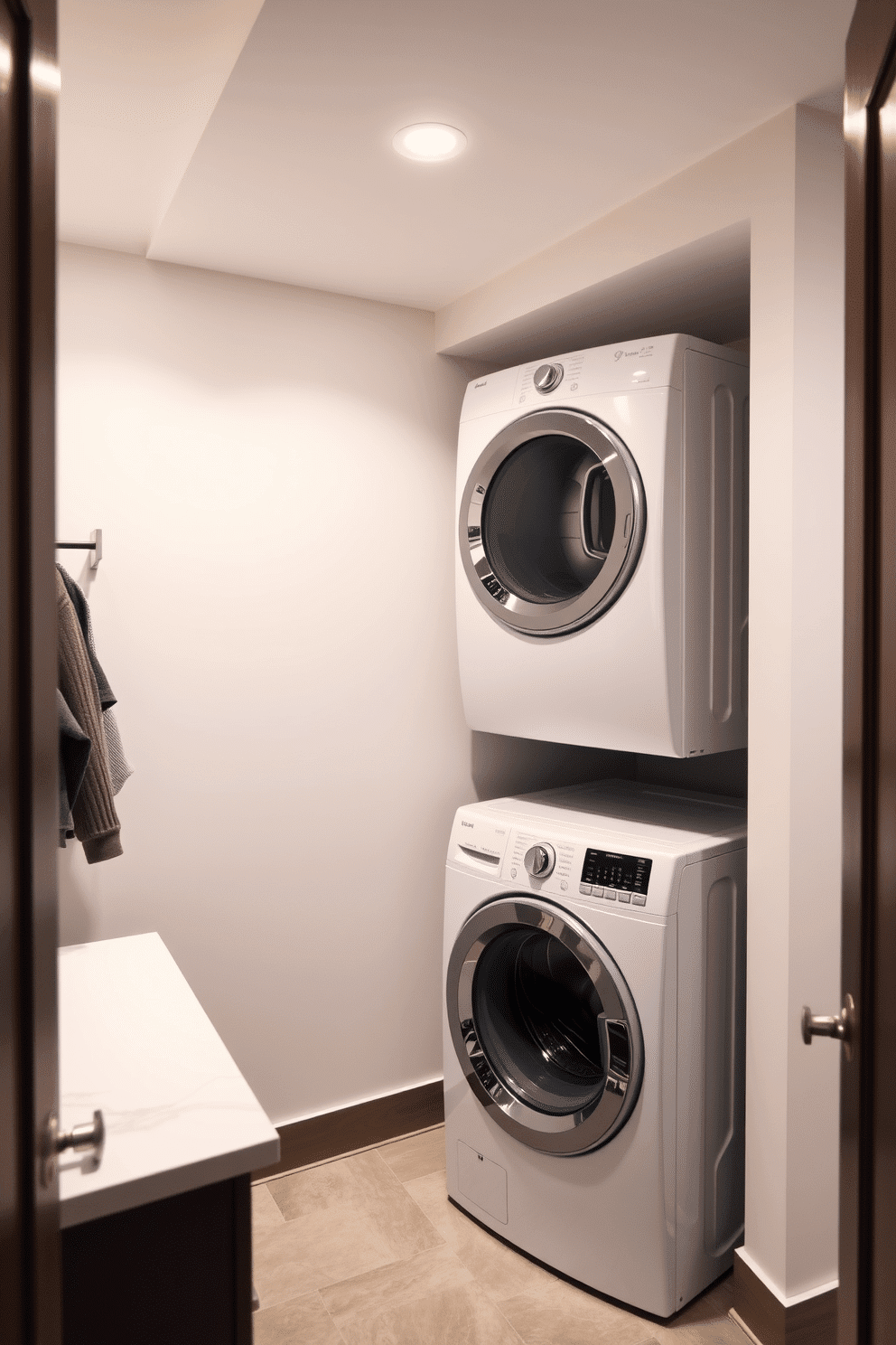 A modern basement laundry room features a stacked washer and dryer unit, maximizing space efficiency in a stylish setting. The room is illuminated by soft, overhead lighting, complemented by a sleek countertop for folding clothes and a wall-mounted shelf for storage.