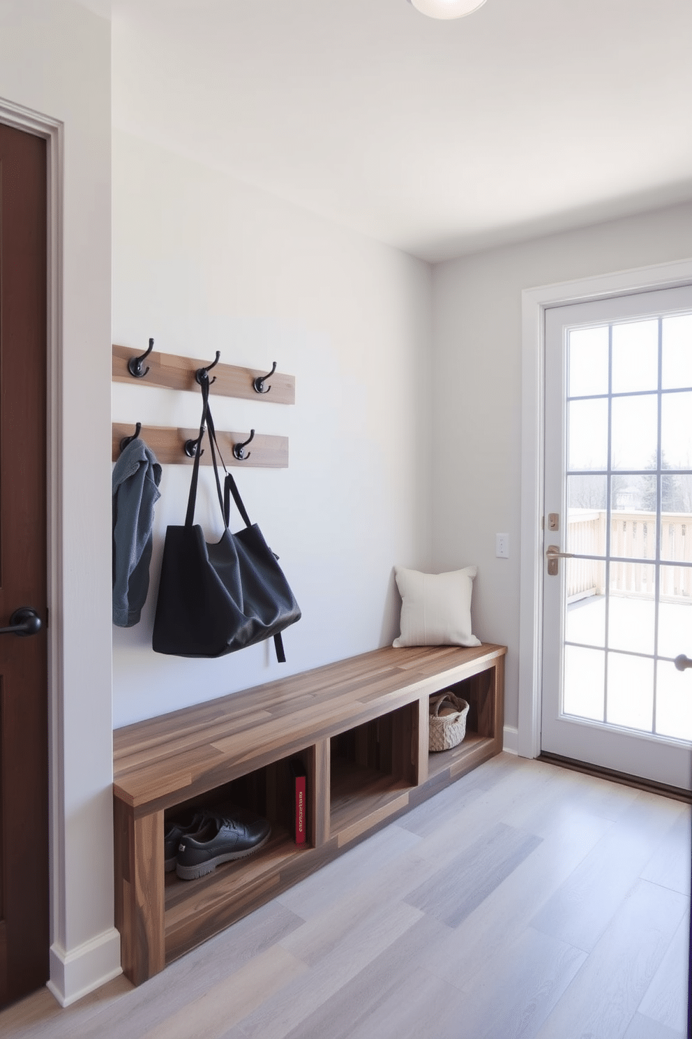 A multi-functional bench with hidden storage is positioned against the wall, crafted from reclaimed wood with a sleek, modern finish. Above the bench, a series of hooks are mounted for coats and bags, while a soft cushion adds comfort and style. The basement mudroom features a durable, water-resistant flooring in a neutral tone, complemented by bright, airy lighting. A large window allows natural light to flood the space, enhancing the welcoming atmosphere while providing easy access to outdoor gear.