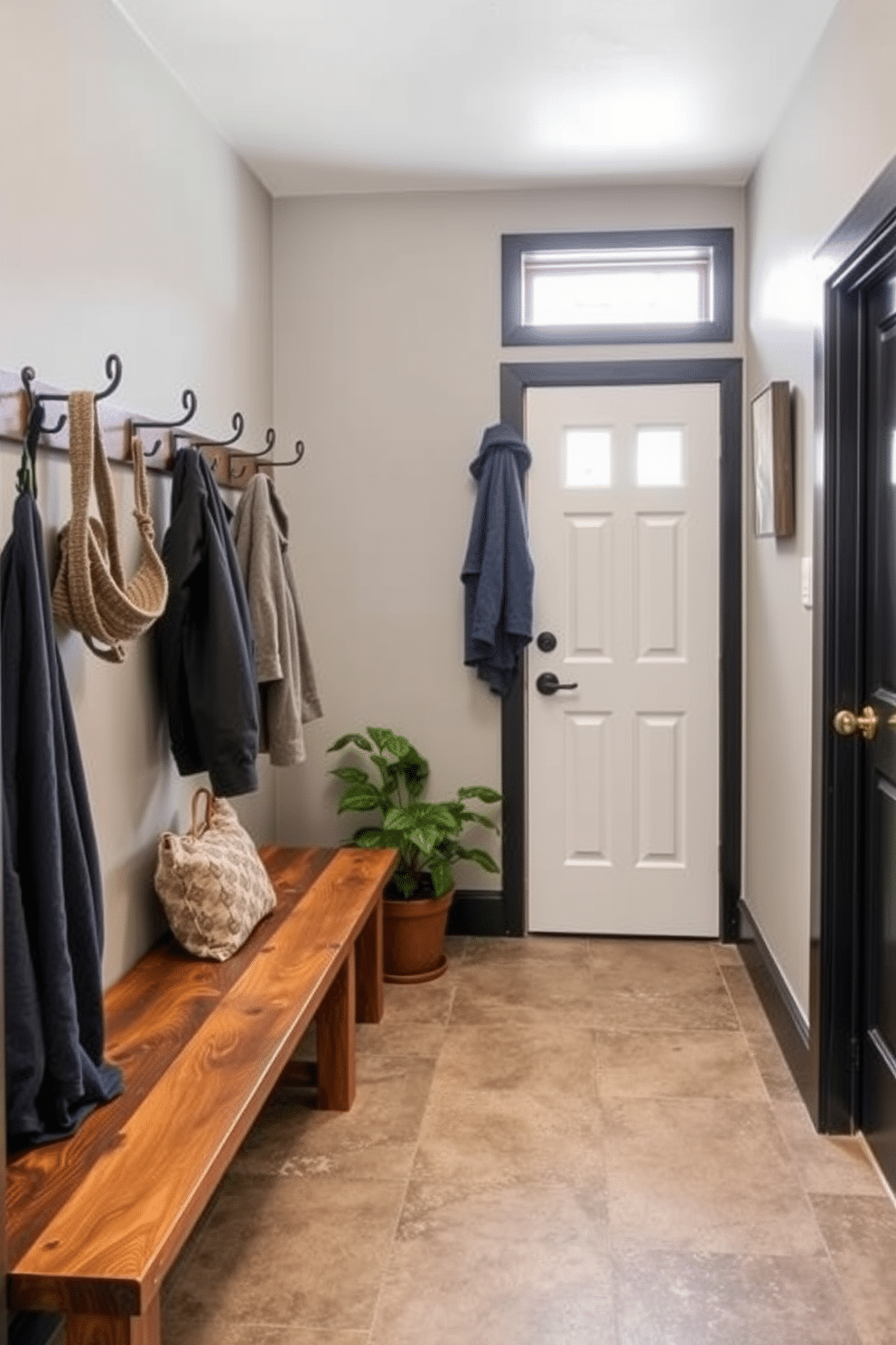 A cozy basement mudroom featuring a combination of rustic wooden benches and sleek metal hooks for coats. Potted plants are strategically placed near the entrance, bringing a touch of greenery and freshness to the space. The walls are painted in a soft gray, complemented by a durable, textured tile floor that withstands heavy foot traffic. Natural light filters in through a small window, enhancing the inviting ambiance of the mudroom.