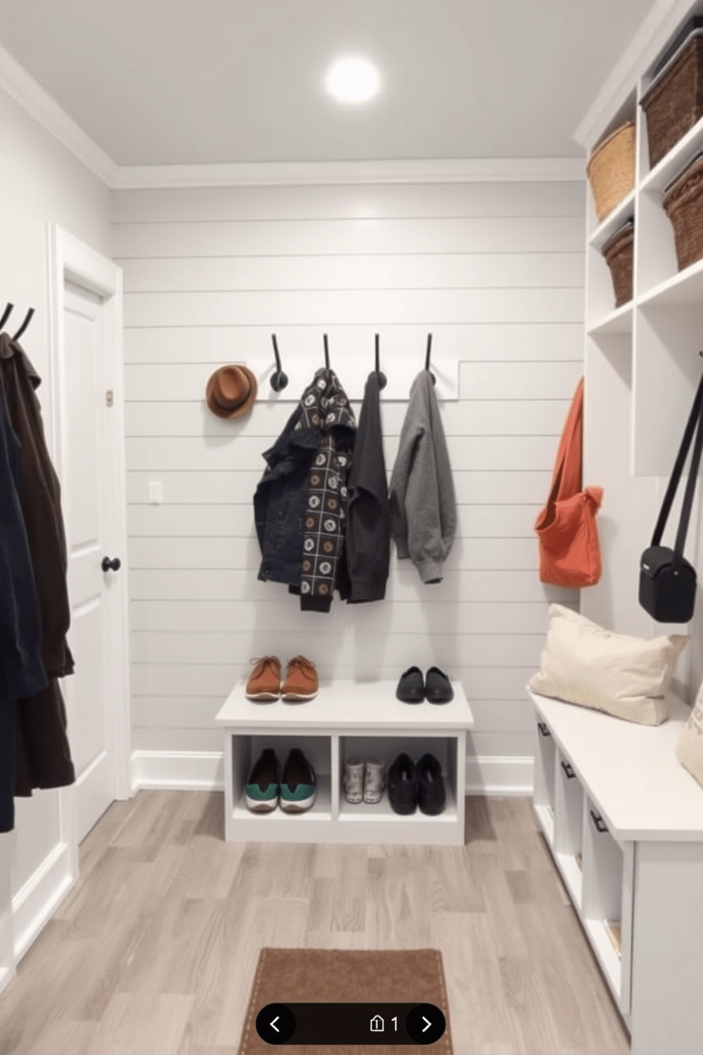 A functional basement mudroom designed for high-traffic use features durable materials such as waterproof vinyl flooring and a sturdy built-in bench. The walls are lined with shiplap painted in a soft gray, while ample storage solutions, including hooks and cubbies, provide organization for shoes and outerwear.