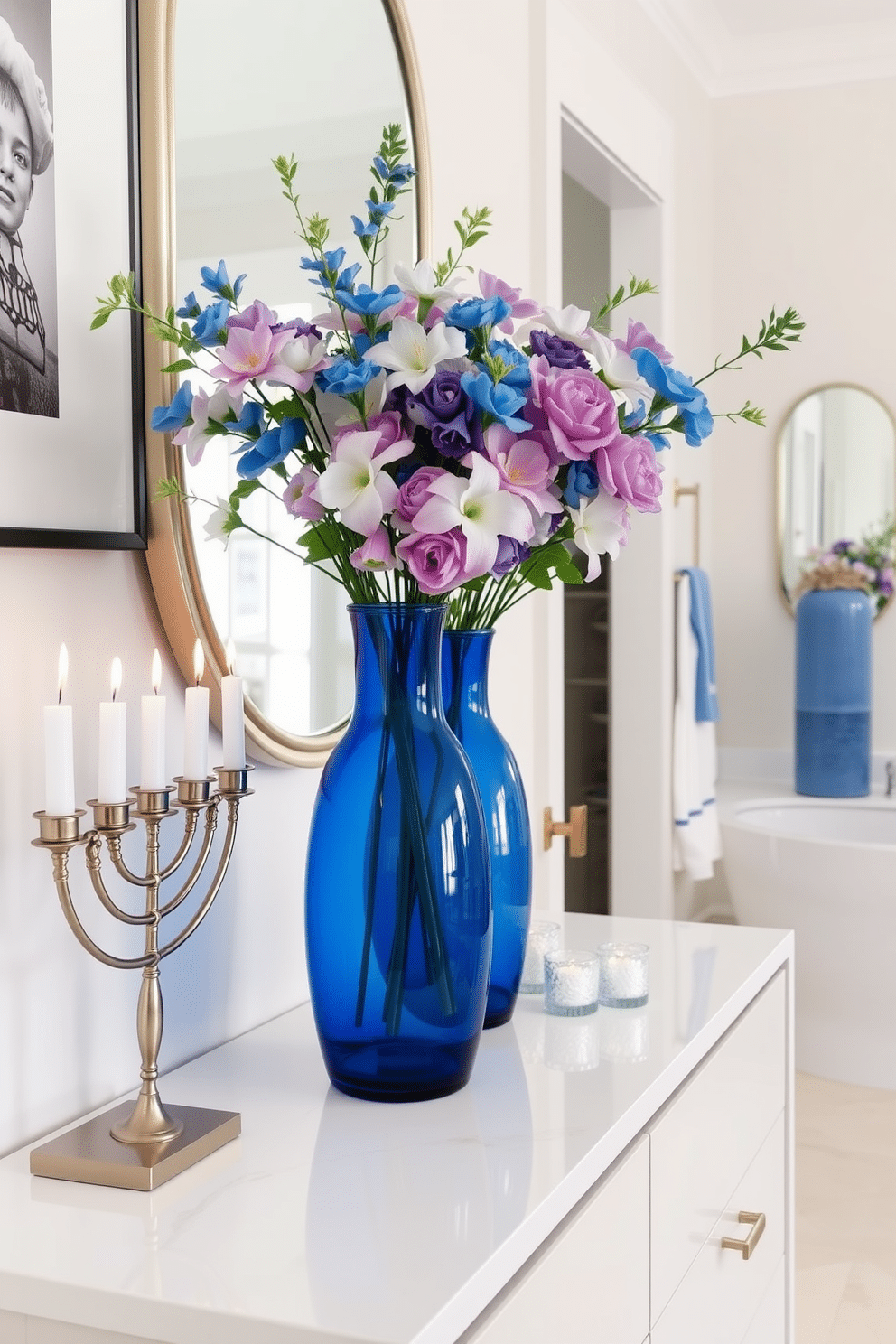 Elegant blue glass vases filled with vibrant flowers sit atop a sleek, modern console table. The vases' rich color contrasts beautifully with the soft, neutral tones of the surrounding decor, creating a stunning focal point in the room. For a festive touch, the bathroom is adorned with subtle Hanukkah decorations. Elegant blue and white accents, such as a menorah and decorative candles, complement the overall design while adding a warm, celebratory atmosphere.