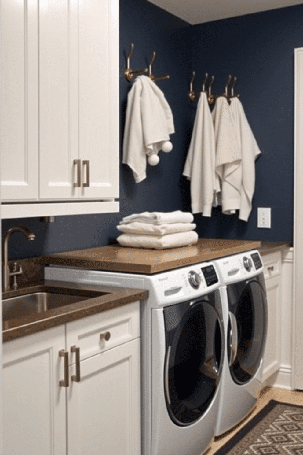 A stylish laundry room that seamlessly combines functionality and aesthetics. The space features a sleek, modern washer and dryer stacked side by side, with a countertop above for folding clothes. On the wall, there are elegant hooks for hanging towels and clothes, adding both convenience and a touch of design. The cabinetry is a soft white, contrasting beautifully with the deep blue walls, while a patterned rug adds warmth to the floor.