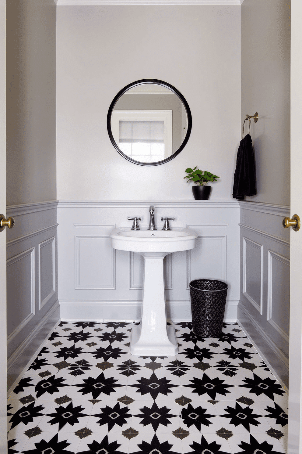 A stylish powder room featuring a bold black and white tile pattern that creates a striking visual impact on the floor. The walls are adorned with elegant wainscoting painted in a soft gray, complementing the dramatic tile choice. In the center, a sleek pedestal sink with a polished chrome faucet stands out against the backdrop. Above the sink, a round mirror with a black frame reflects the room's chic design, while a small potted plant adds a touch of greenery to the space.