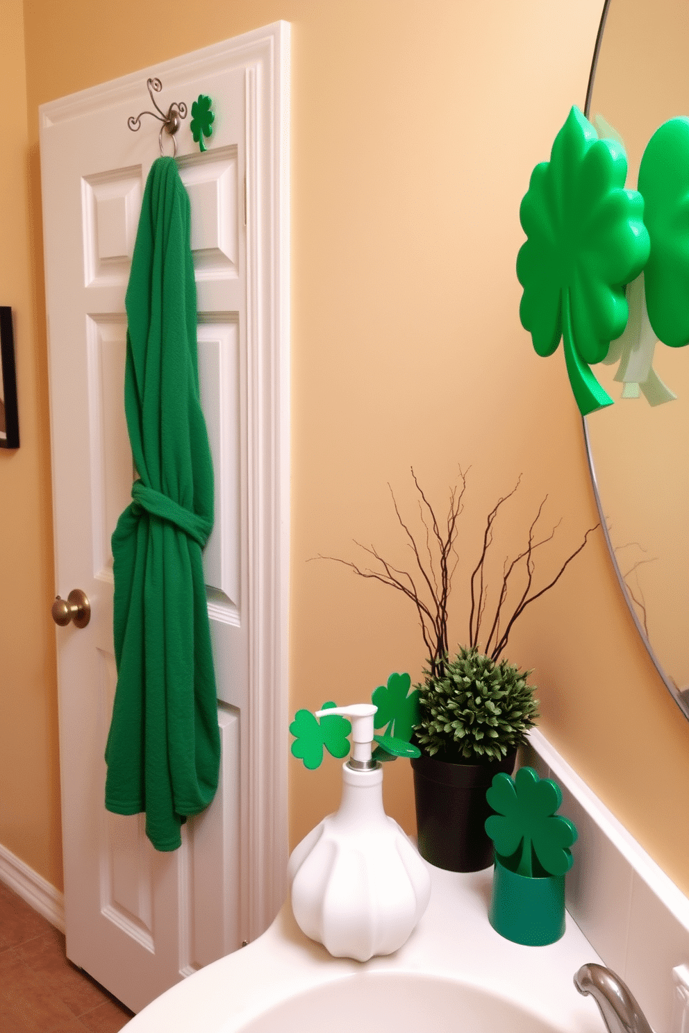 A cozy bathroom setting adorned for St. Patrick's Day. A green bathrobe and matching slippers hang from a decorative hook near the door, while festive shamrock-themed decorations are tastefully arranged on the countertop. The walls are painted a soft cream, providing a warm backdrop for the vibrant green accents. A small potted shamrock plant sits next to a white ceramic soap dispenser, adding a touch of nature to the festive decor.