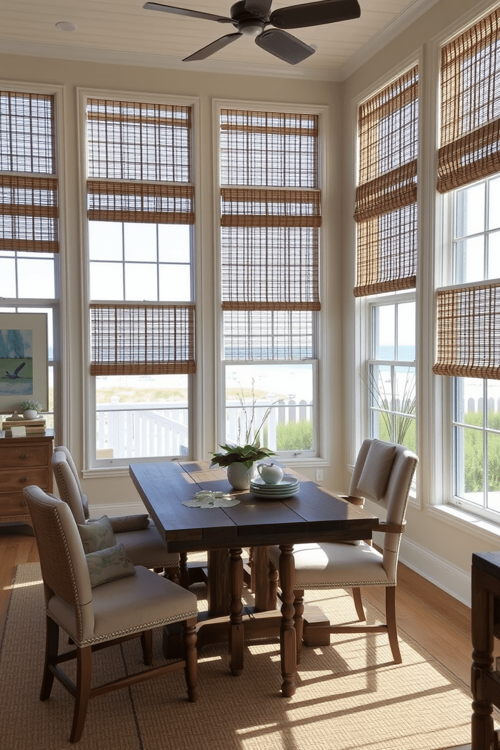 A beach dining room featuring large windows adorned with bamboo blinds that filter natural light, creating a warm and inviting atmosphere. The space includes a rustic wooden dining table surrounded by comfortable, upholstered chairs, complemented by coastal-inspired decor and soft blue accents.