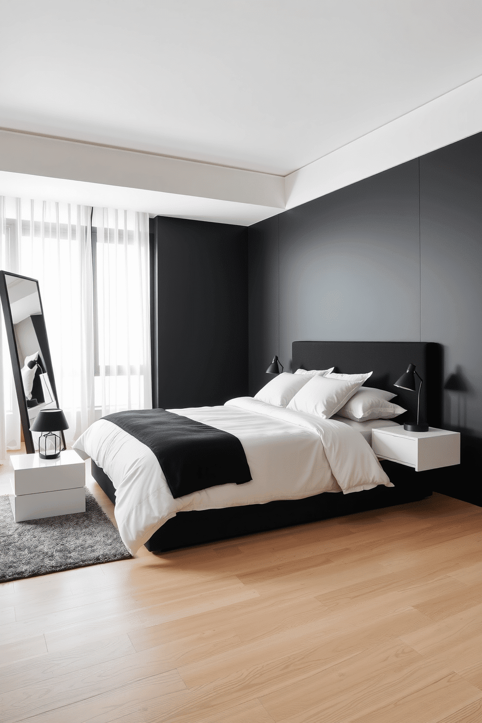 A sleek and minimalist bedroom with a black feature wall that contrasts elegantly with crisp white bedding. The bed is framed by a low-profile black platform and flanked by simple white nightstands adorned with geometric black table lamps. The floor is finished in light, natural wood, adding warmth to the monochrome palette. A large black-framed mirror leans casually against one wall, reflecting soft natural light from sheer white curtains framing expansive windows.