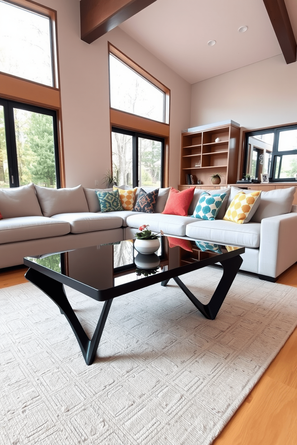 A stylish black coffee table with a sleek glass top sits at the center of a modern family room. The room features a plush sectional sofa in a light gray fabric, accented with colorful throw pillows that add a pop of vibrancy. Warm wood tones are incorporated through a media console against one wall, complementing the black coffee table. Large windows allow natural light to flood the space, enhancing the cozy atmosphere and showcasing a tasteful area rug beneath the coffee table.