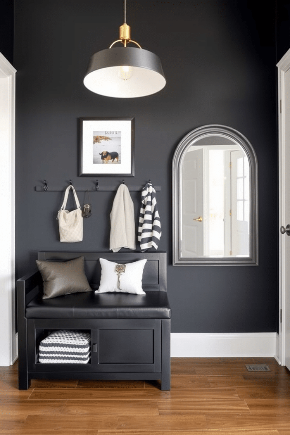 Chic black entryway bench with storage. The bench features a sleek design with a cushioned top, perfect for sitting while putting on shoes, and hidden compartments for storing bags and accessories. The foyer is adorned with a statement wall in a deep charcoal hue, complemented by stylish wall hooks for coats. A modern pendant light fixture hangs above, casting a warm glow over the space, while a large mirror reflects light and enhances the sense of openness.