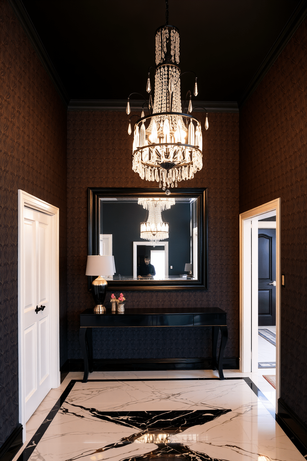 An elegant black chandelier with crystal details hangs gracefully from the ceiling, casting a warm glow across the foyer. The walls are adorned with rich, dark wallpaper, and a sleek console table with a glossy finish sits against one side, topped with decorative accents. The floor features polished marble tiles in a classic black and white pattern, enhancing the luxurious feel of the space. A large mirror with an ornate black frame reflects the chandelier's brilliance, creating an inviting and sophisticated entrance.