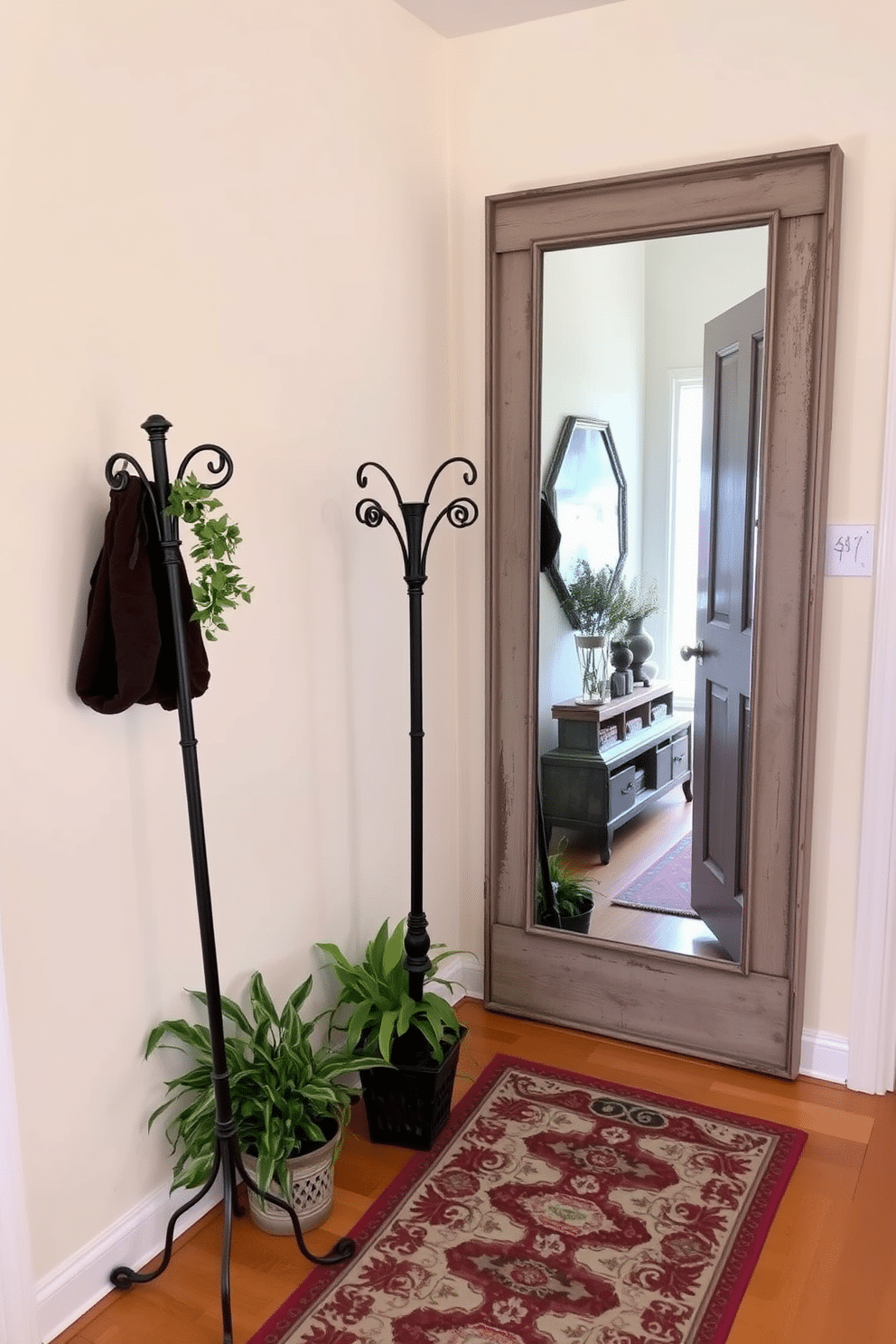 A vintage black coat rack stands elegantly against the wall in a stylish foyer. The space is adorned with a patterned runner rug and a large mirror framed in distressed wood, reflecting the charm of the room. The walls are painted in a soft cream color, enhancing the warmth of the vintage elements. Potted plants flank the coat rack, adding a touch of greenery and life to the inviting entrance.