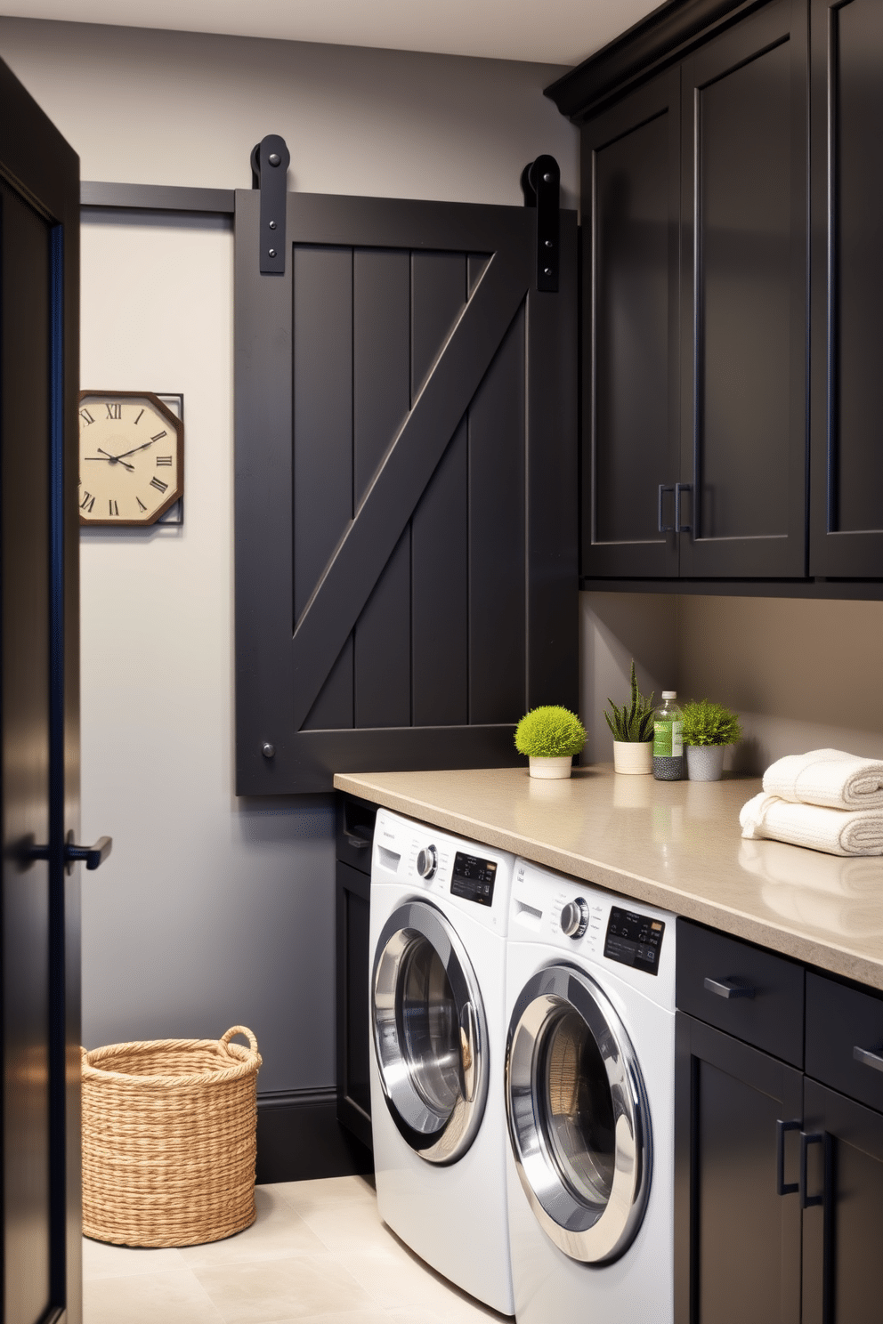 A stylish laundry room featuring a black sliding barn door that adds a rustic charm. The space is equipped with sleek black cabinets, a modern washer and dryer, and a spacious countertop for folding clothes. The walls are painted in a soft gray hue, providing a contemporary contrast to the dark cabinetry. A decorative laundry basket and potted plants add a touch of warmth and personality to the room.