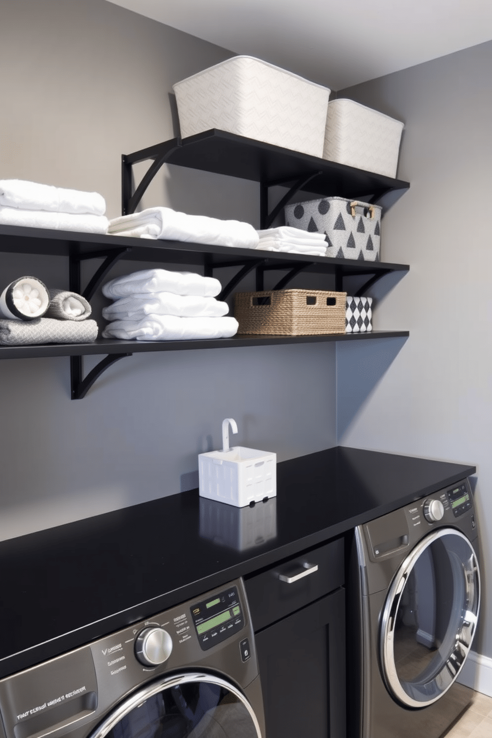 A stylish black laundry room features open shelving with black brackets, displaying neatly folded towels and decorative storage bins. The walls are painted in a soft gray, complemented by a sleek black countertop and modern appliances, creating a chic and functional space.