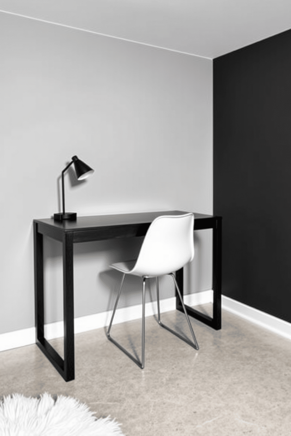 A minimalist black desk is positioned against a light grey wall, featuring clean lines and a sleek surface. Accompanying the desk is a modern white chair with a simple yet elegant design, creating a striking contrast in the space. The basement design incorporates a monochromatic theme, with black walls and white accents throughout. A plush white rug lays on the polished concrete floor, adding warmth and texture to the otherwise stark environment.