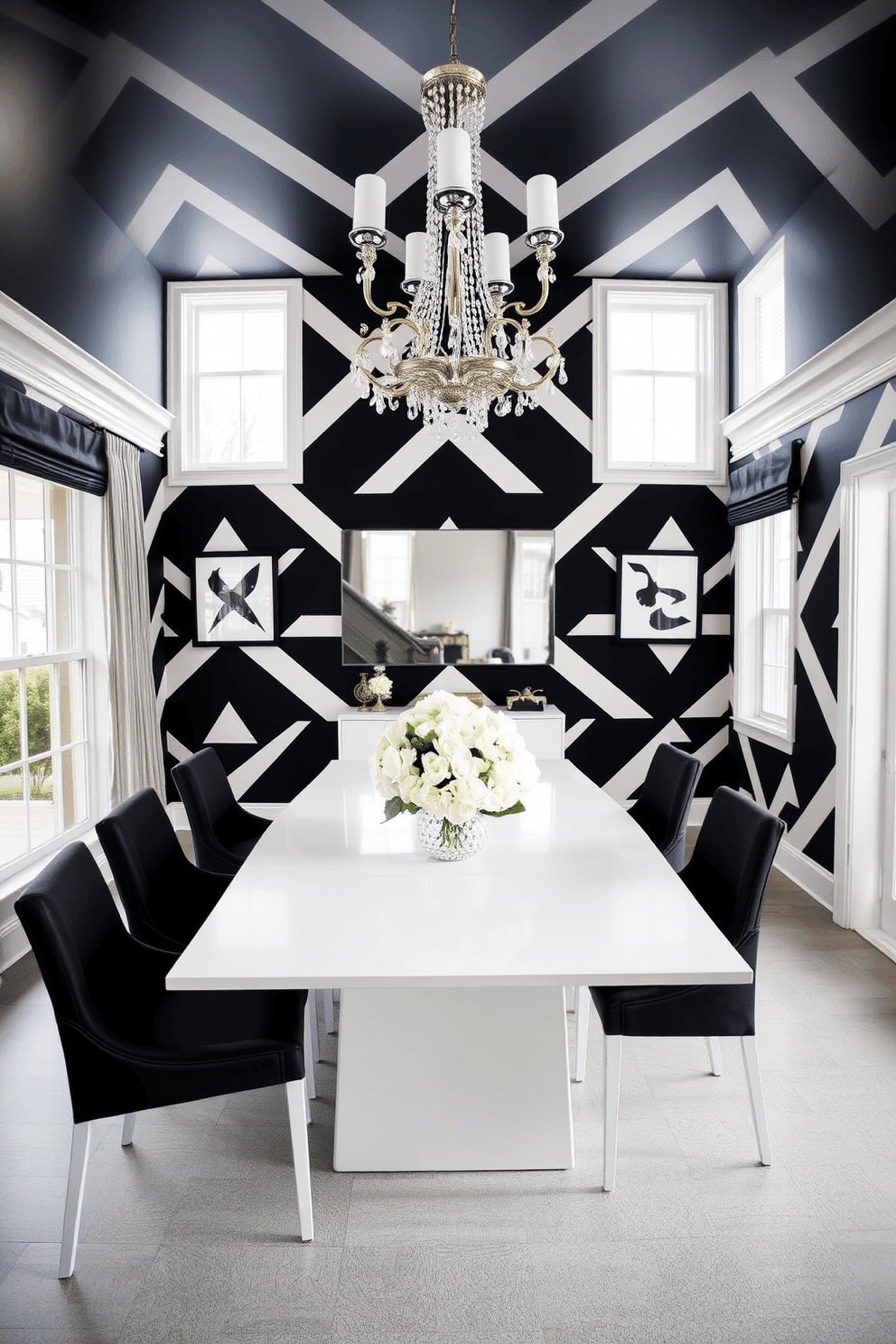 A striking dining room features bold black and white geometric wallpaper that creates a dramatic focal point. The room is furnished with a sleek white dining table surrounded by black upholstered chairs, complemented by a contemporary chandelier overhead. Natural light floods the space through large windows, highlighting the contrast between the dark wallpaper and the light furnishings. A statement centerpiece of fresh white flowers adds a touch of elegance to the table, enhancing the overall sophisticated atmosphere.