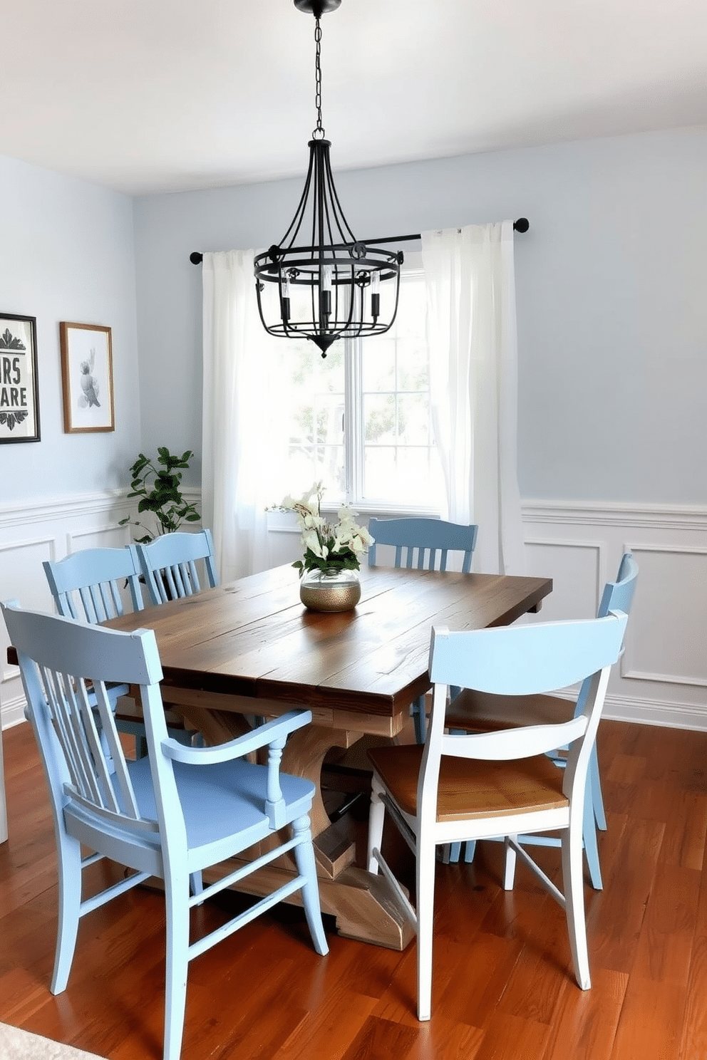 A charming dining room featuring a rustic farmhouse table made of reclaimed wood, surrounded by mismatched chairs in light blue hues. The walls are painted in a soft light blue, complemented by white wainscoting and a large window draped with sheer white curtains that allow natural light to flood the space.