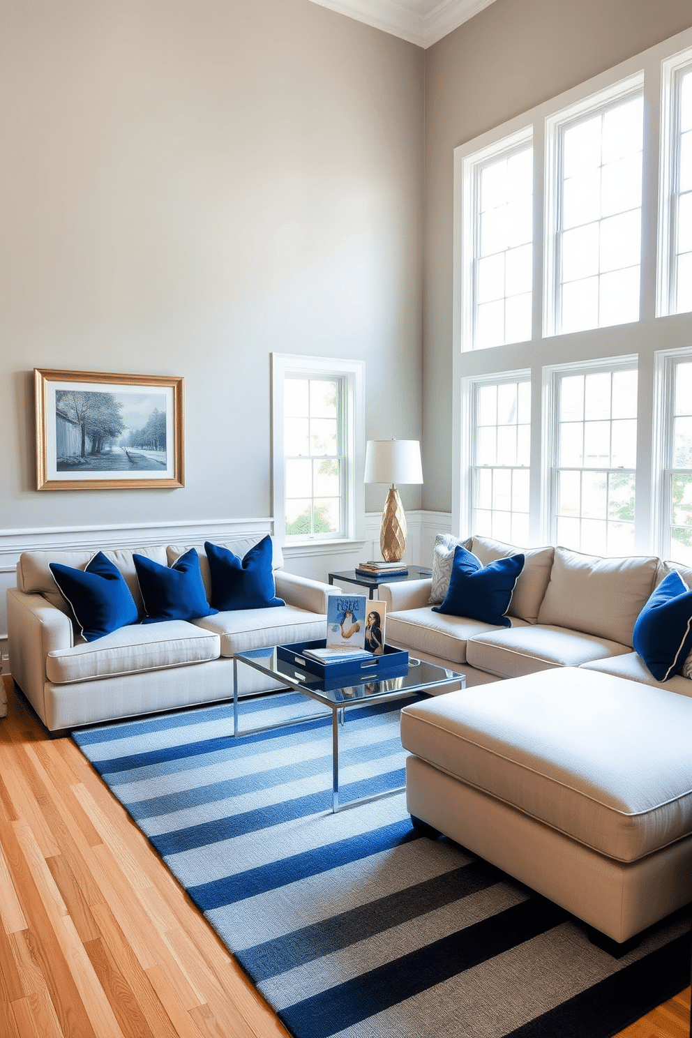 A classic blue and white striped rug anchors the family room, adding a touch of timeless elegance. The space features a plush sectional sofa in a soft beige fabric, complemented by navy blue accent pillows that enhance the color palette. Natural light floods the room through large windows, highlighting the light wood flooring and creating a warm ambiance. A stylish coffee table sits at the center, adorned with a few art books and a decorative tray, inviting relaxation and conversation.