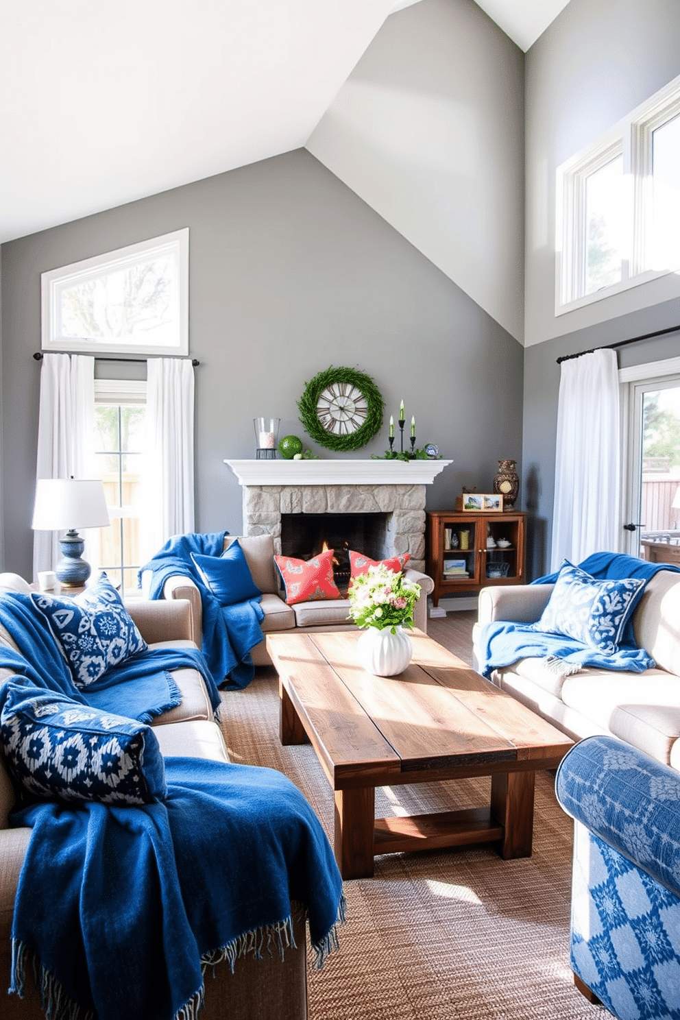 A cozy family room with denim blue throw blankets draped over plush sofas, creating an inviting atmosphere. The walls are painted in a soft gray, complementing the deep blue tones of the decor and enhancing the room's warmth. Natural light floods the space through large windows adorned with sheer white curtains. A rustic wooden coffee table sits in the center, surrounded by vibrant cushions that add a pop of color to the blue theme.