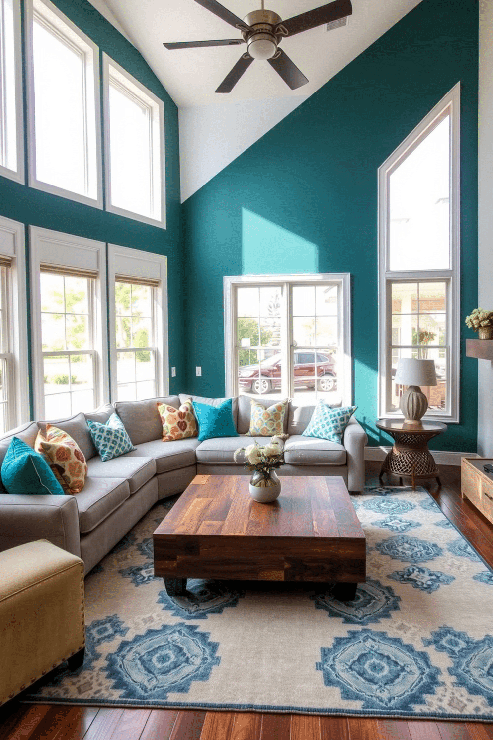 A cozy family room featuring an accent wall in a deep teal color that adds a rich, inviting atmosphere. The room is furnished with a plush sectional sofa in a light gray fabric, paired with colorful throw pillows that complement the accent wall. A large area rug anchors the seating area, showcasing a mix of geometric patterns in blue and cream. Natural light pours in through oversized windows, highlighting a stylish coffee table made of reclaimed wood at the center of the room.