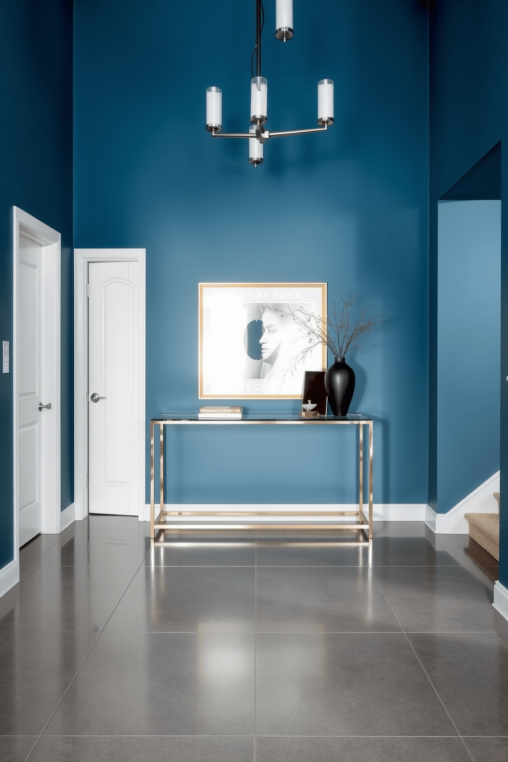 A striking foyer featuring a steel blue accent wall that sets a calming tone for the space. Sleek metallic finishes adorn the light fixtures and hardware, reflecting light and adding a touch of modern elegance. The floor is adorned with large, polished tiles in a complementary shade, enhancing the overall aesthetic. A minimalist console table with a glass top sits against the wall, topped with a stylish vase and a few curated decorative items.