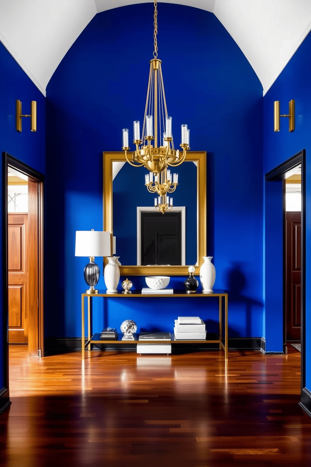 A striking foyer features bold cobalt blue walls that create a vibrant backdrop. Gold fixtures, including a statement chandelier and sleek wall sconces, add a touch of luxury and elegance to the space. The flooring consists of rich hardwood that complements the blue and gold palette. A stylish console table adorned with decorative accents and a large mirror enhances the foyer's inviting atmosphere.