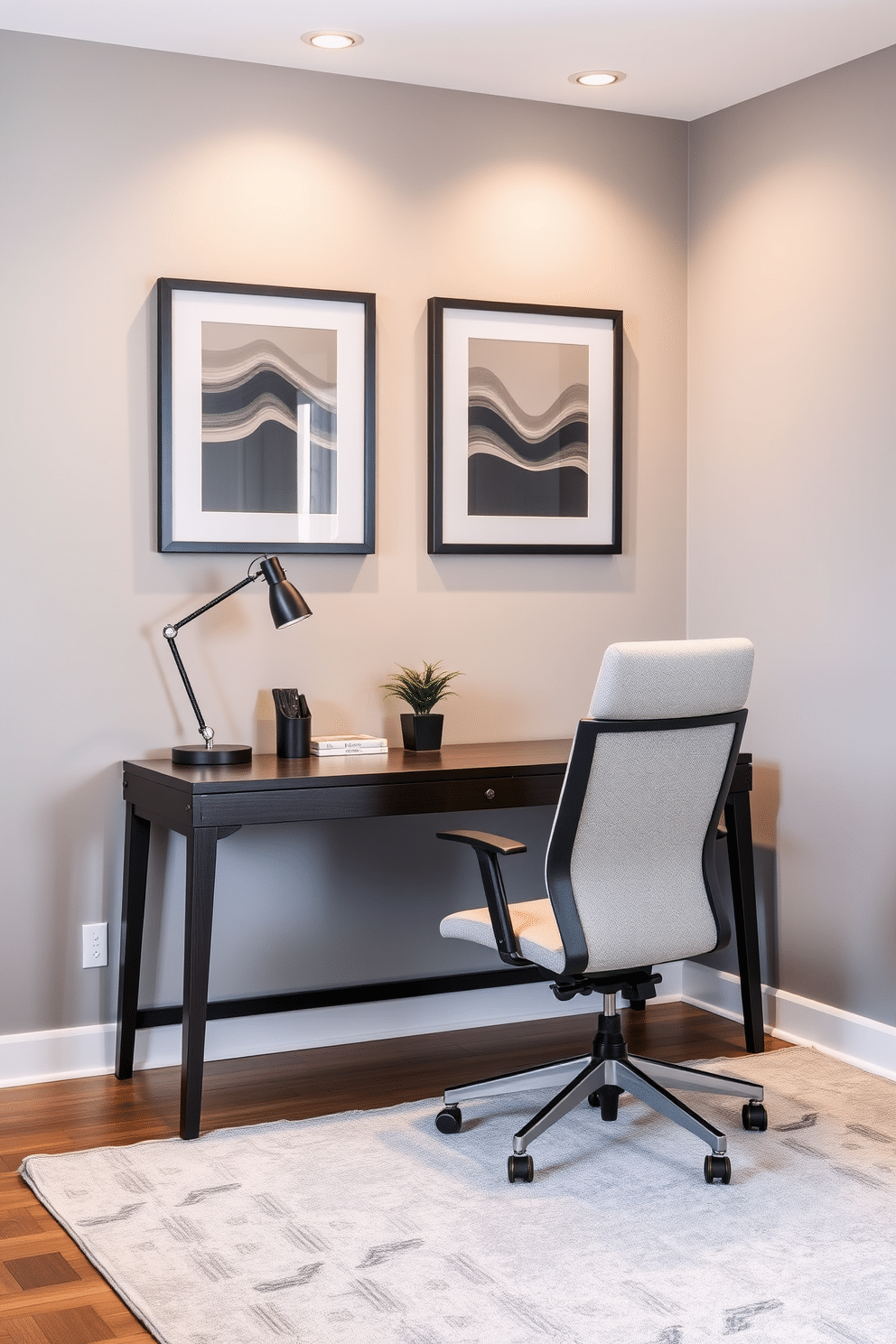 A modern home office featuring a sleek desk with a dark wood finish, positioned against a wall painted in a soft gray hue. Above the desk, dark blue framed art pieces add a pop of color and sophistication, while a stylish desk lamp provides warm lighting. The room is accessorized with a comfortable ergonomic chair upholstered in a light fabric, enhancing both style and comfort. A plush area rug in muted tones anchors the space, and a small potted plant adds a touch of greenery to the overall design.