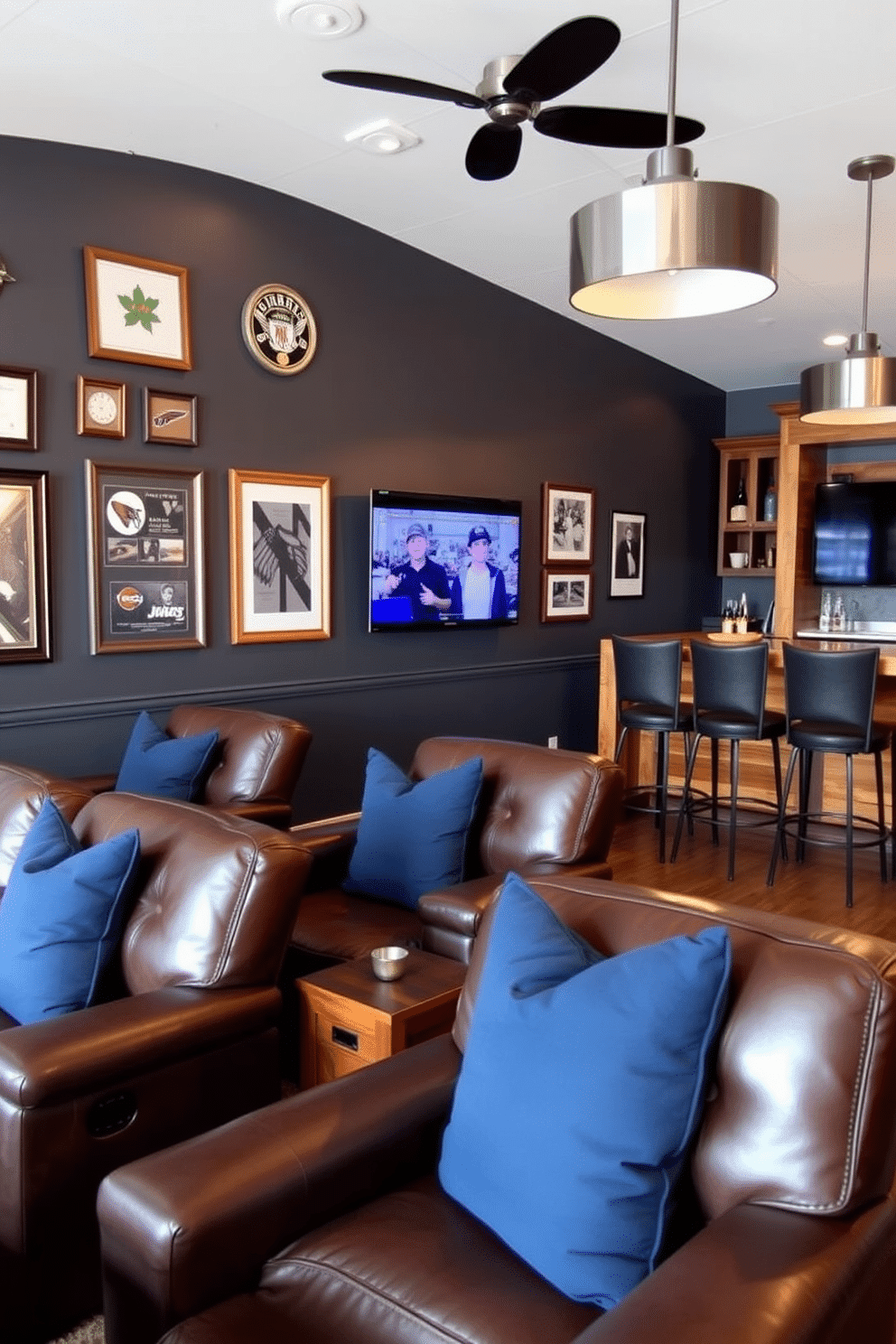 A stylish man cave featuring leather recliners adorned with navy throw pillows, creating a cozy yet sophisticated atmosphere. The walls are painted in a deep charcoal gray, with framed sports memorabilia and a mounted flat-screen TV for entertainment. A custom-built bar area complements the seating, crafted from reclaimed wood with high stools that invite socializing. Ambient lighting is provided by sleek pendant lights, enhancing the overall warmth of the space.