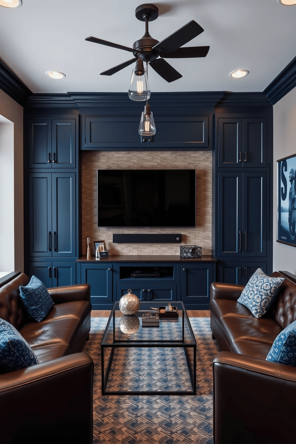 A stylish man cave featuring a wall-mounted TV surrounded by custom cabinetry that blends seamlessly with the room's decor. The cabinetry is finished in a deep navy blue, complementing the rich leather seating and industrial-style lighting fixtures overhead. The space is designed for relaxation and entertainment, with plush seating arranged for optimal viewing and a sleek coffee table at the center. Accents of metallic decor and artwork in shades of blue enhance the overall ambiance, creating a sophisticated yet cozy atmosphere.