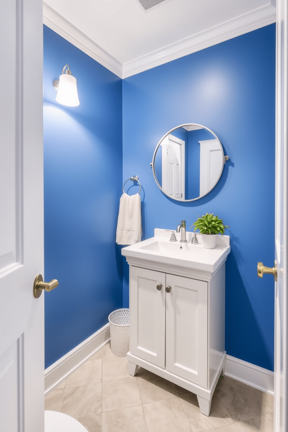 A chic powder room featuring a striking blue accent wall that creates a bold focal point. The decor is kept neutral, with a sleek white vanity and a round mirror framed in brushed nickel, complemented by soft lighting. The floor is adorned with light gray tiles, providing a subtle contrast to the vibrant wall. Accents of greenery are introduced with a small potted plant on the vanity, adding a refreshing touch to the space.