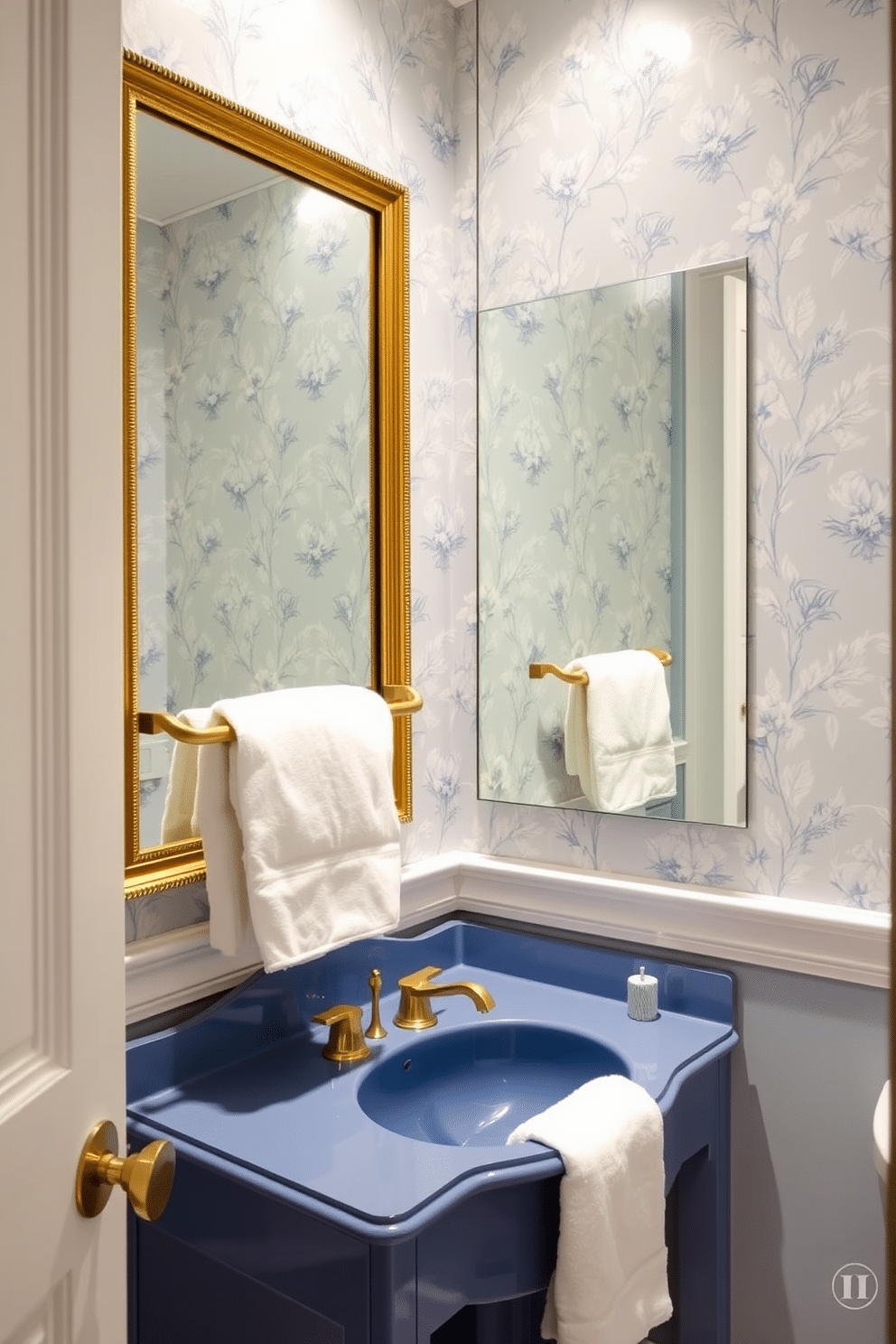 A stunning powder room features a blue sink with elegant gold fixtures, perfectly complementing the overall color scheme. Above the sink, a large gold-framed mirror adds a touch of luxury and reflects the soft ambient lighting. The walls are adorned with a delicate floral wallpaper in shades of blue and white, creating a serene atmosphere. A stylish gold towel bar holds a plush white towel, enhancing the room's sophisticated appeal.