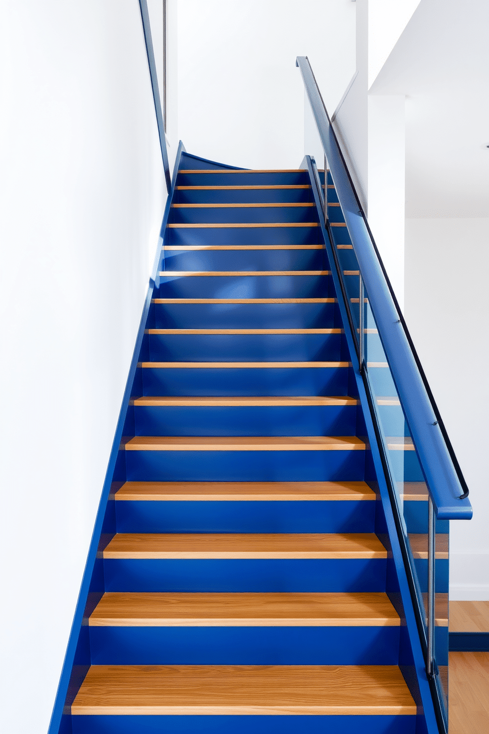 A sleek navy blue staircase ascends gracefully, featuring clean lines and a minimalist design that emphasizes simplicity and elegance. The surrounding walls are painted in a soft white, creating a striking contrast that highlights the staircase as a focal point in the space. The treads are made of polished wood, while the risers are a matte navy finish, enhancing the modern aesthetic. A glass railing runs alongside, allowing natural light to flow through and accentuate the staircase's bold color.