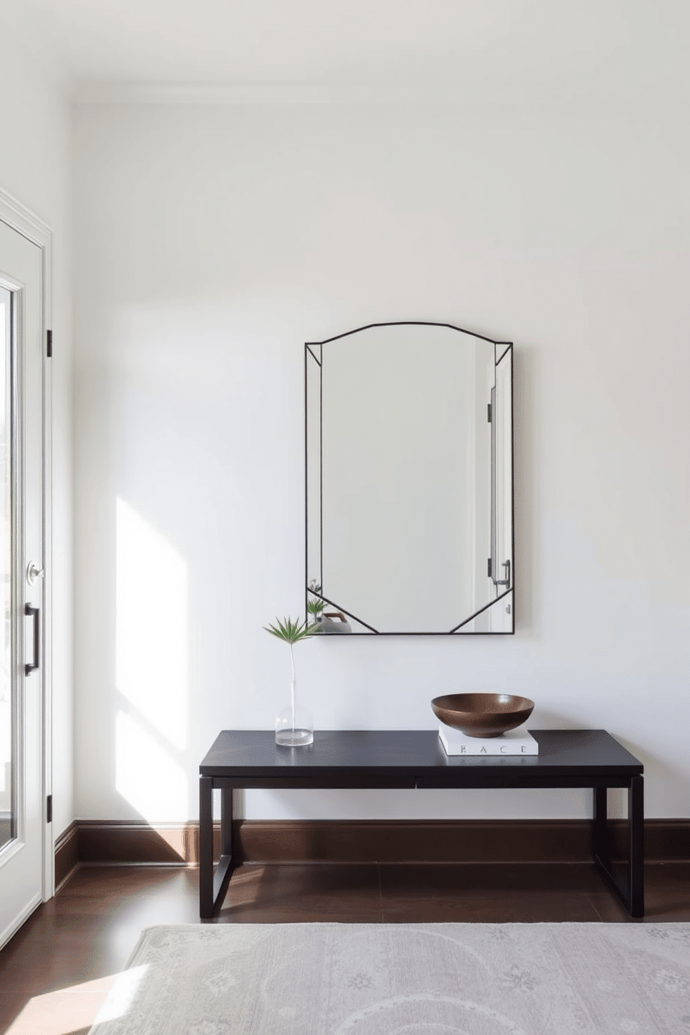 A sleek console table made of dark wood is positioned against the wall, topped with a decorative bowl and a small potted plant. Above it hangs a large geometric mirror that reflects the light, creating an illusion of space and adding a modern touch to the foyer. The walls are painted in a soft white, enhancing the airy feel of the room, while a stylish area rug in muted tones anchors the space. Natural light streams in through a nearby window, illuminating the contemporary design elements and inviting a warm, welcoming atmosphere.