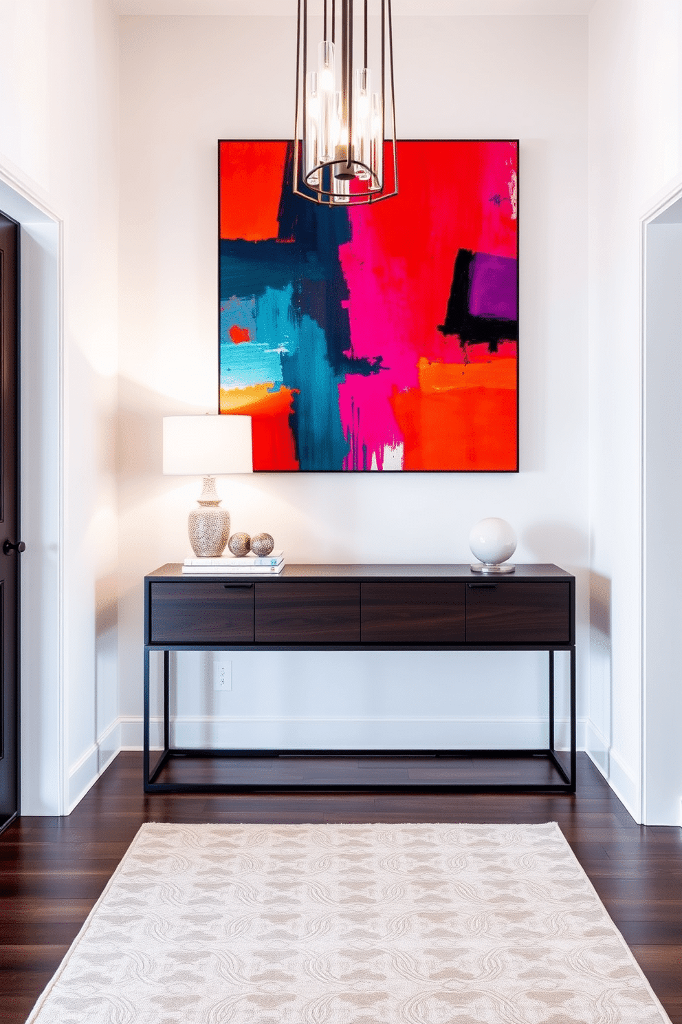 A contemporary foyer featuring a striking piece of artwork with vibrant colors that draws the eye upon entry. The walls are painted in a soft white, providing a clean backdrop for the bold hues of the artwork, while a sleek console table in a dark wood adds sophistication. The space is illuminated by a modern chandelier that casts a warm glow, enhancing the inviting atmosphere. A plush area rug in neutral tones anchors the space, and a few carefully selected decorative items on the console table add a personal touch.