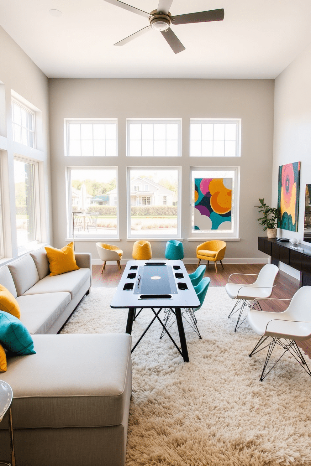 A contemporary game room featuring a neutral color palette with pops of vibrant colors. The space includes a sleek sectional sofa in light gray, accented with bright throw pillows in shades of teal and mustard. A modern game table is placed in the center, surrounded by stylish chairs that complement the color scheme. Large windows allow natural light to flood the room, highlighting the colorful artwork on the walls and the plush area rug beneath the table.