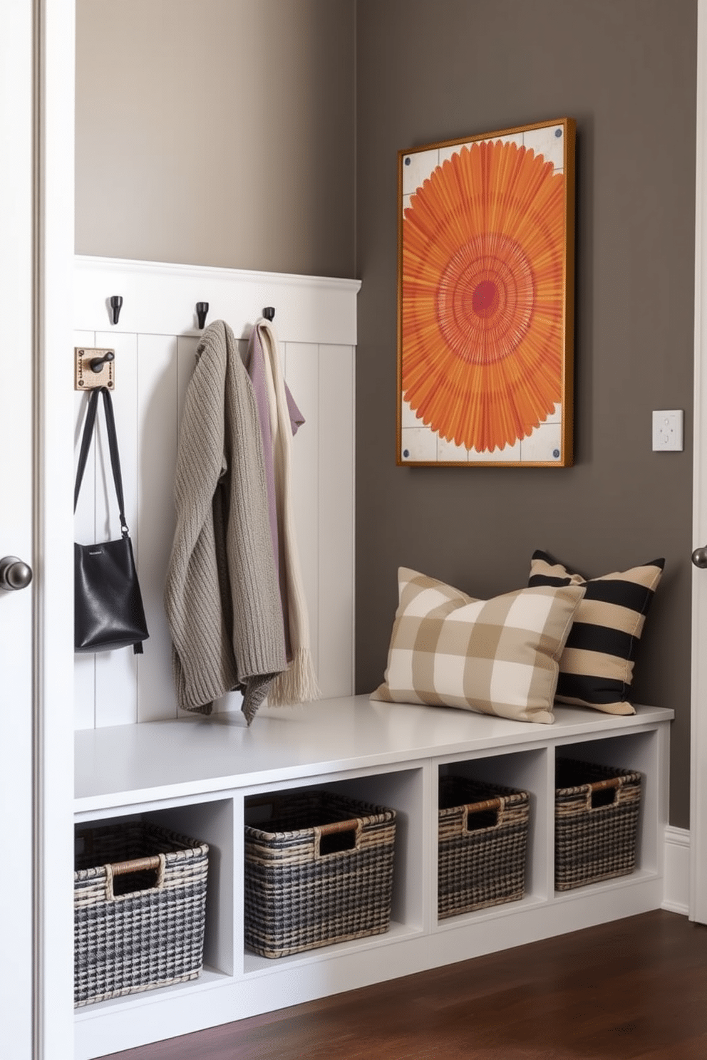 A contemporary mudroom features stylish baskets that blend seamlessly with the decor, providing a chic solution for hidden clutter. The space includes a built-in bench with storage underneath, accented by a sleek coat rack and vibrant wall art, creating an inviting entryway.