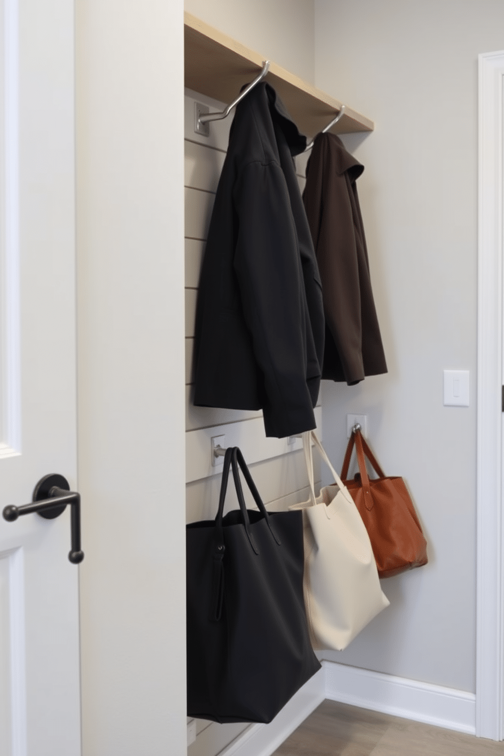 A contemporary mudroom features sleek wall-mounted hooks for coats and bags, providing both functionality and style. The space is designed with a minimalist aesthetic, showcasing a neutral color palette and durable materials that can withstand everyday wear.