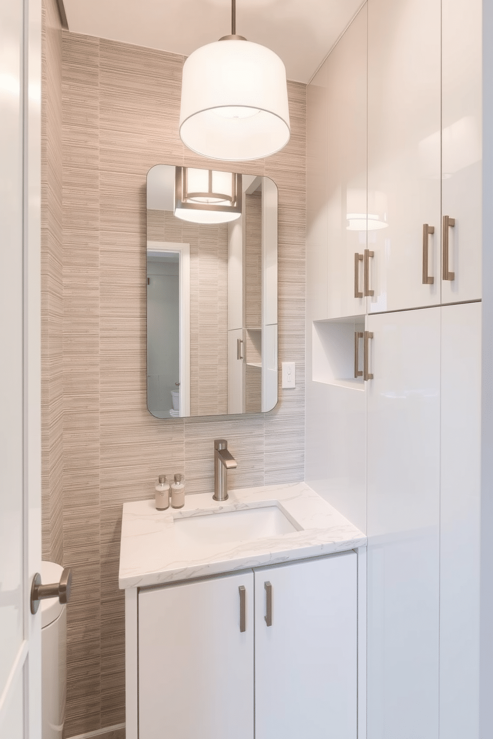 A sleek contemporary powder room features custom cabinetry that maximizes space and offers tailored storage solutions. The cabinetry is finished in a high-gloss white, complementing the elegant marble countertop and modern fixtures. The walls are adorned with a textured wallpaper in soft gray tones, creating a sophisticated backdrop. A stylish pendant light hangs above, illuminating the space and highlighting the minimalist design elements.