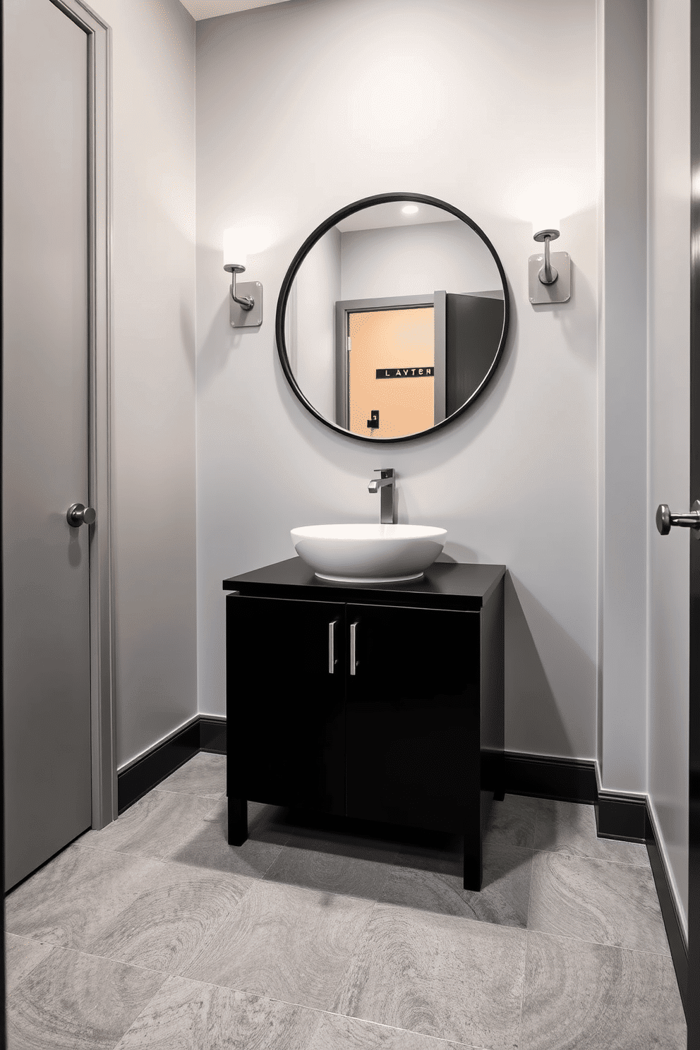 A contemporary powder room featuring a monochromatic color scheme that exudes elegance. The walls are painted in a soft gray, complemented by a sleek black vanity with a white vessel sink. The flooring consists of large gray tiles with a subtle texture, enhancing the room's modern aesthetic. A round mirror with a minimalist black frame hangs above the vanity, reflecting ambient lighting from stylish sconces on either side.