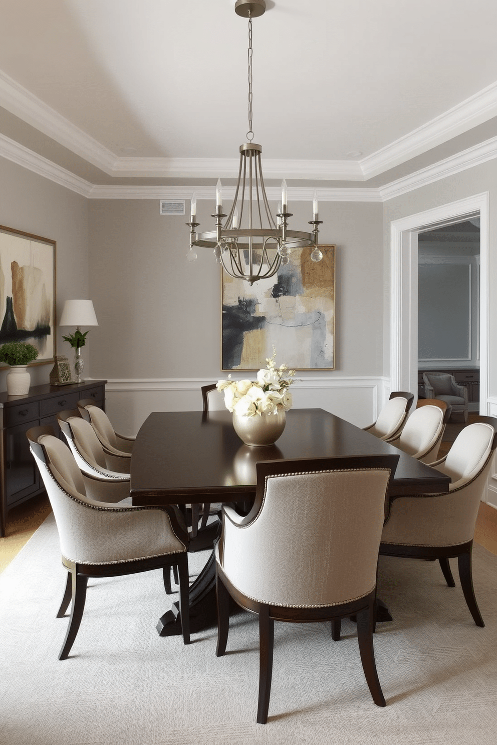 A transitional dining room that harmoniously blends traditional and contemporary elements. The table is a dark wood with elegant, curved legs, surrounded by upholstered chairs in a neutral fabric, creating a warm and inviting atmosphere. A statement chandelier hangs above the table, featuring a mix of metal finishes for a modern touch. The walls are adorned with a soft gray paint, while a large piece of abstract art adds a pop of color to the space.