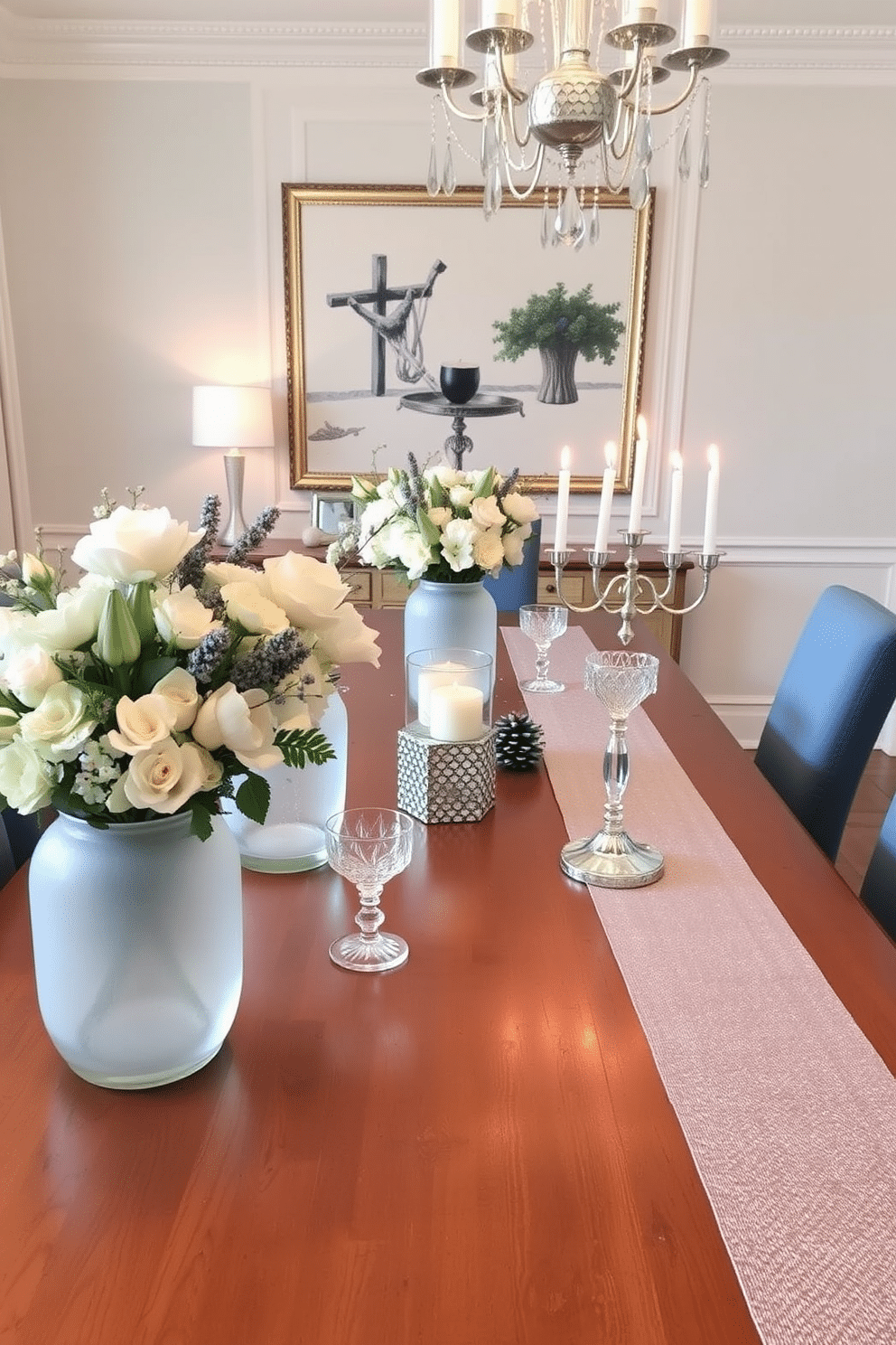 A stylish dining room adorned for Hanukkah features a long wooden table set with elegant frosted glass vases filled with seasonal blooms. Soft blue and silver accents create a festive atmosphere, complemented by shimmering table runners and decorative menorahs placed strategically along the table.