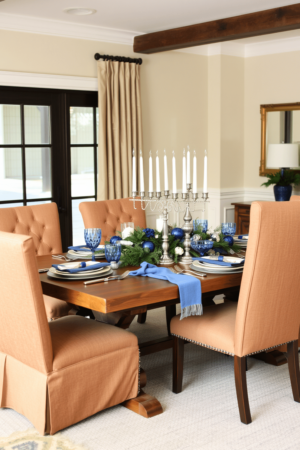 A cozy dining room adorned with soft fabric textures. Plush upholstered chairs in a warm neutral tone surround a rustic wooden table, creating an inviting atmosphere for gatherings. Festive Hanukkah decorations enhance the space with a touch of elegance. A beautifully arranged table centerpiece features blue and silver accents, including a menorah and seasonal greenery, setting the perfect mood for celebration.