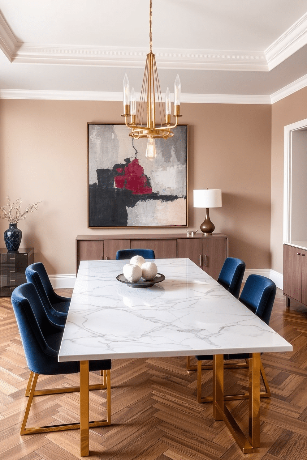 A stunning dining room features an elegant marble top dining table with sleek, gold legs that add a touch of luxury. Surrounding the table are plush velvet chairs in a deep navy hue, complemented by a contemporary chandelier hanging above. The walls are painted in a soft taupe, creating a warm and inviting atmosphere. A large abstract painting in coordinating colors serves as a focal point, while a chic sideboard against one wall provides additional storage and display space.