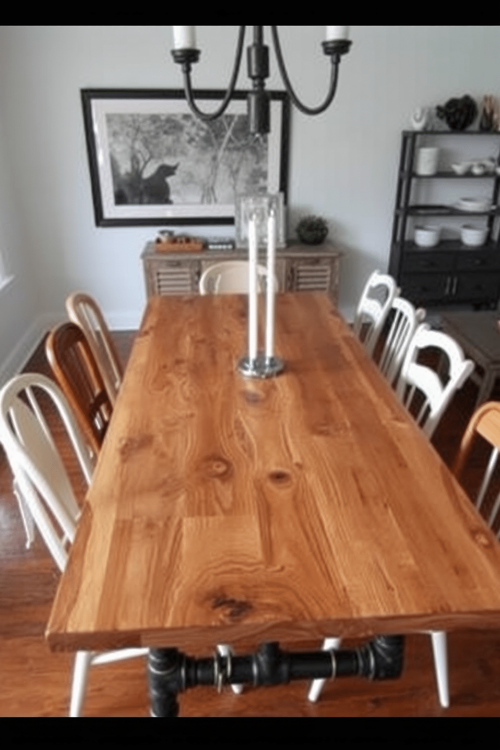 A striking dining room features an industrial pipe table crafted from reclaimed wood, showcasing its natural grain and unique character. Surrounding the table are mismatched vintage chairs, adding an eclectic charm to the space while complementing the industrial aesthetic.