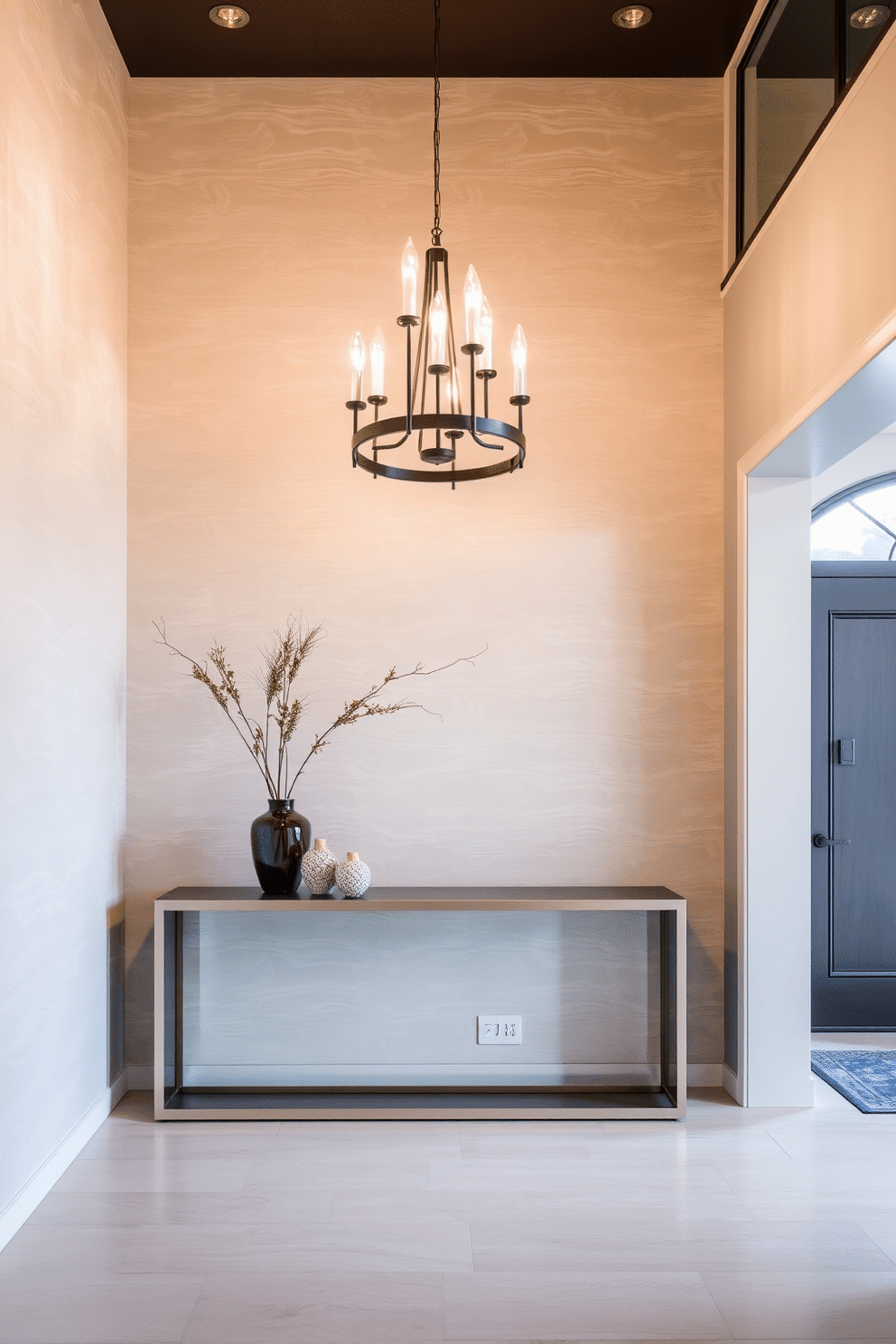 A stunning entrance foyer featuring textured wall panels that add depth and visual interest. The space is illuminated by a modern chandelier, casting a warm glow over a sleek console table adorned with decorative accents.