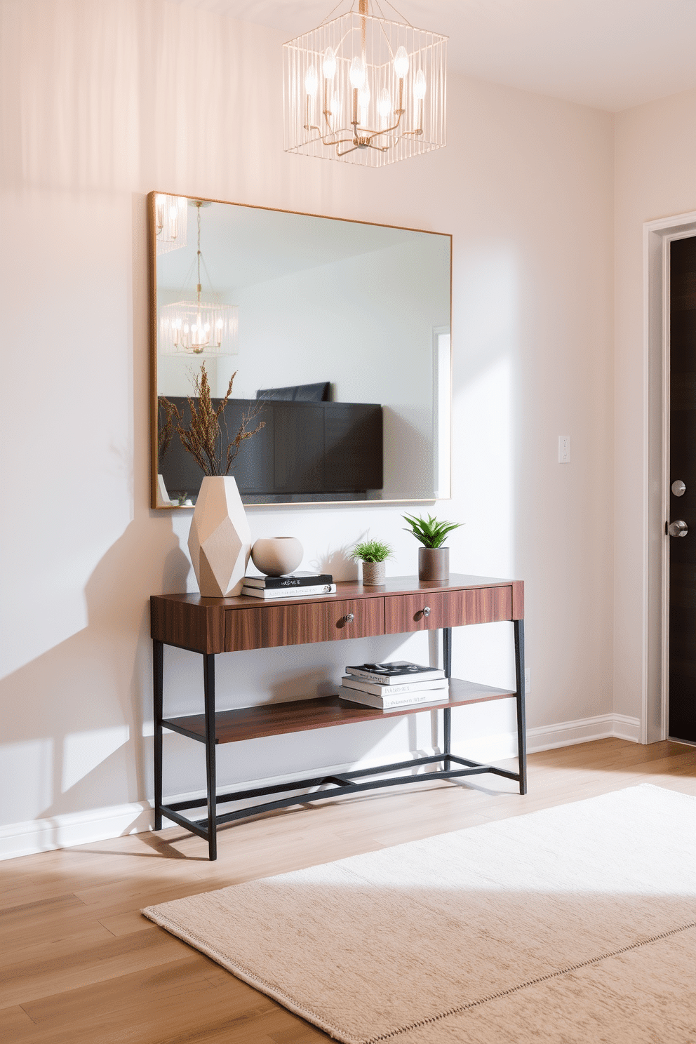 A stylish console table is positioned against a light gray wall, featuring a sleek design with a rich walnut finish. On top of the table, a collection of decorative accents includes a geometric vase, a stack of art books, and a small potted plant, adding a touch of greenery. The entrance foyer is illuminated by a modern chandelier that hangs elegantly from the ceiling, casting a warm glow over the space. A plush area rug in soft neutral tones anchors the foyer, while a large mirror above the console table enhances the sense of openness and light.