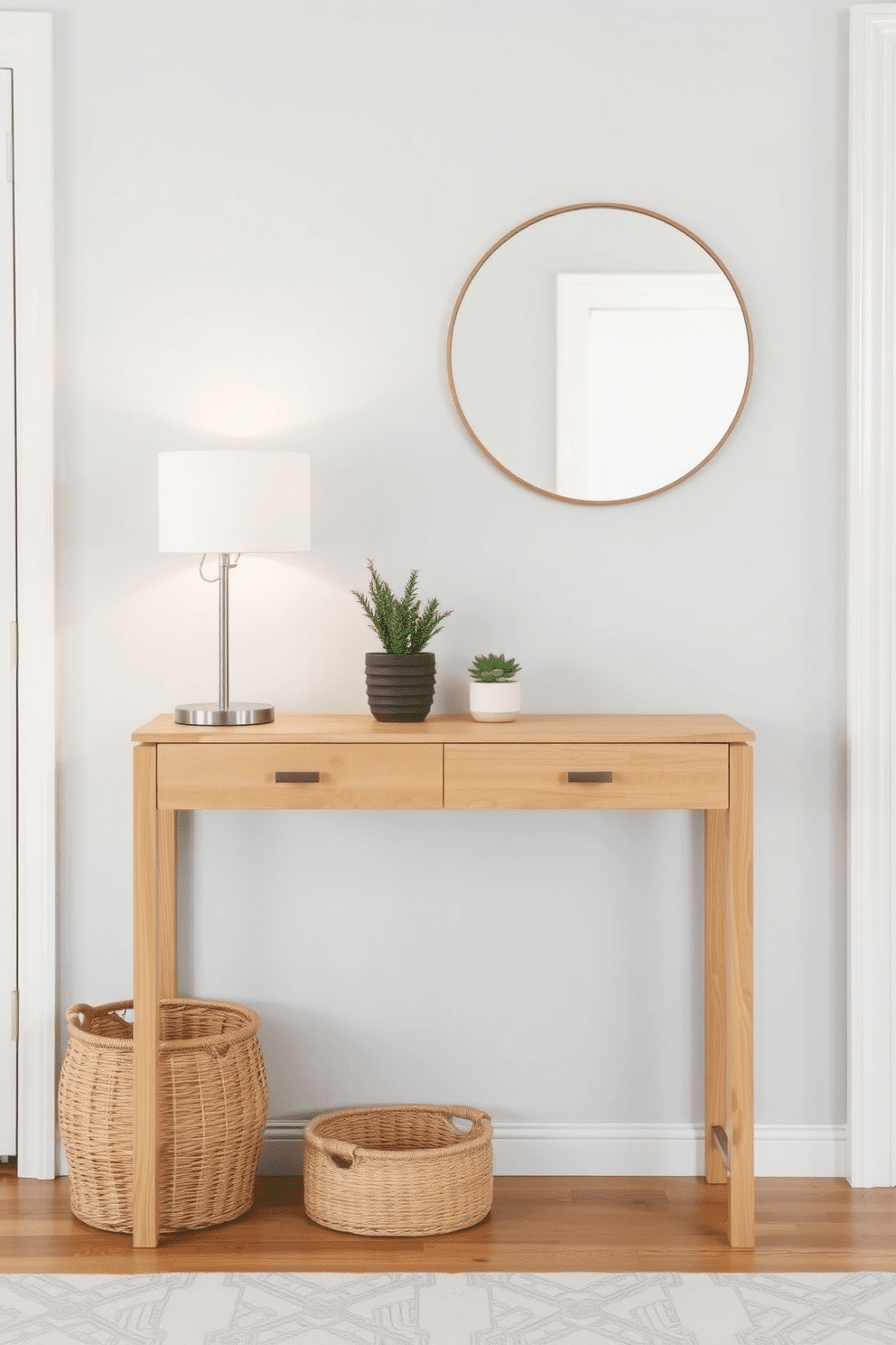 A minimalist console table is positioned against a soft gray wall, creating a serene entryway atmosphere. The table features clean lines and a natural wood finish, adorned with a few potted succulents and a sleek, modern lamp. To the side, a stylish round mirror reflects the space, enhancing the sense of openness. A woven basket underneath the table provides storage for shoes, while a subtle area rug adds warmth and texture to the floor.