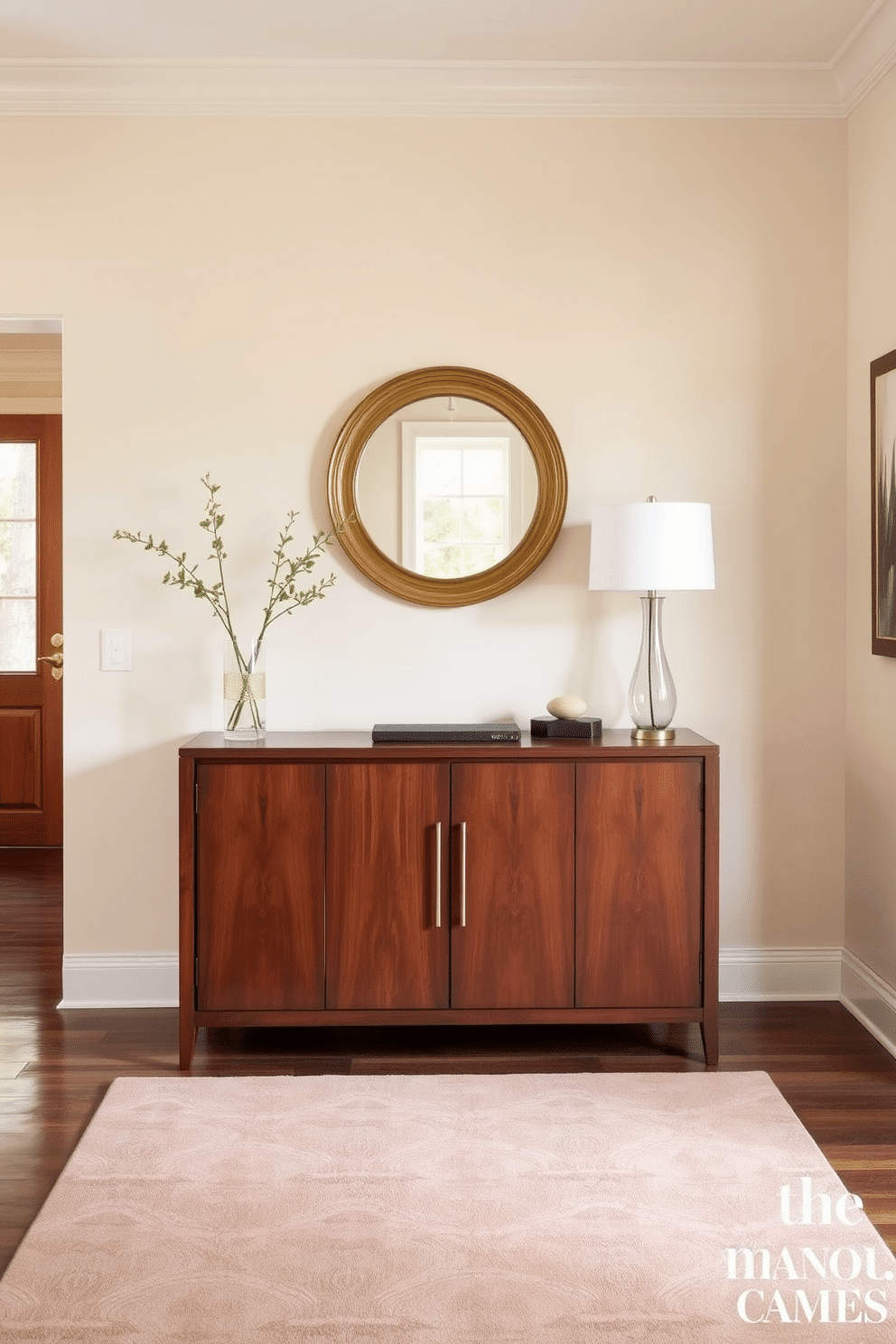 A welcoming entryway features a cohesive color scheme with soft beige walls that complement a rich walnut console table. Above the table, a round mirror with a gold frame reflects natural light, while a stylish rug in muted tones anchors the space. Flanking the console are decorative elements like a pair of elegant vases filled with fresh greenery and a chic lamp that adds warmth. The overall design is enhanced by a carefully chosen artwork that ties together the color palette, creating a harmonious first impression.