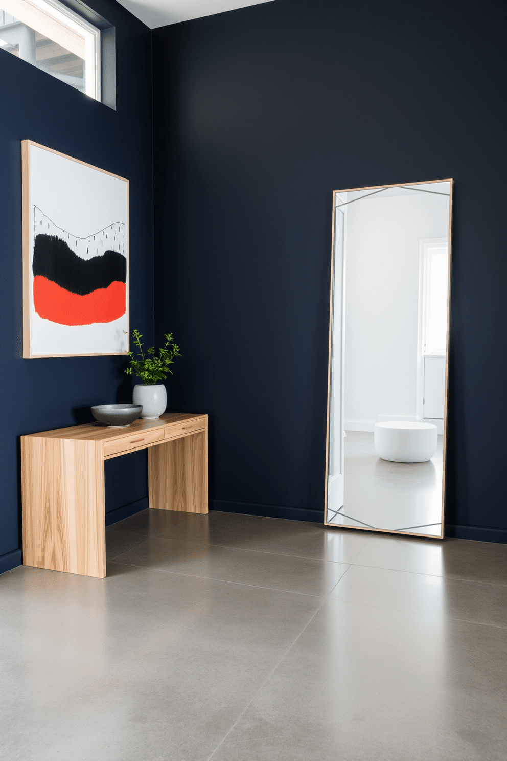 A modern entryway featuring a striking art piece as the focal point. The walls are adorned with a deep navy blue, while the floor is a sleek polished concrete, creating a contemporary backdrop for the artwork. A minimalist console table made of light oak stands against one wall, topped with a small potted plant and a stylish bowl. To the side, a large mirror with a geometric frame reflects the art piece, enhancing the sense of space and light in the entryway.