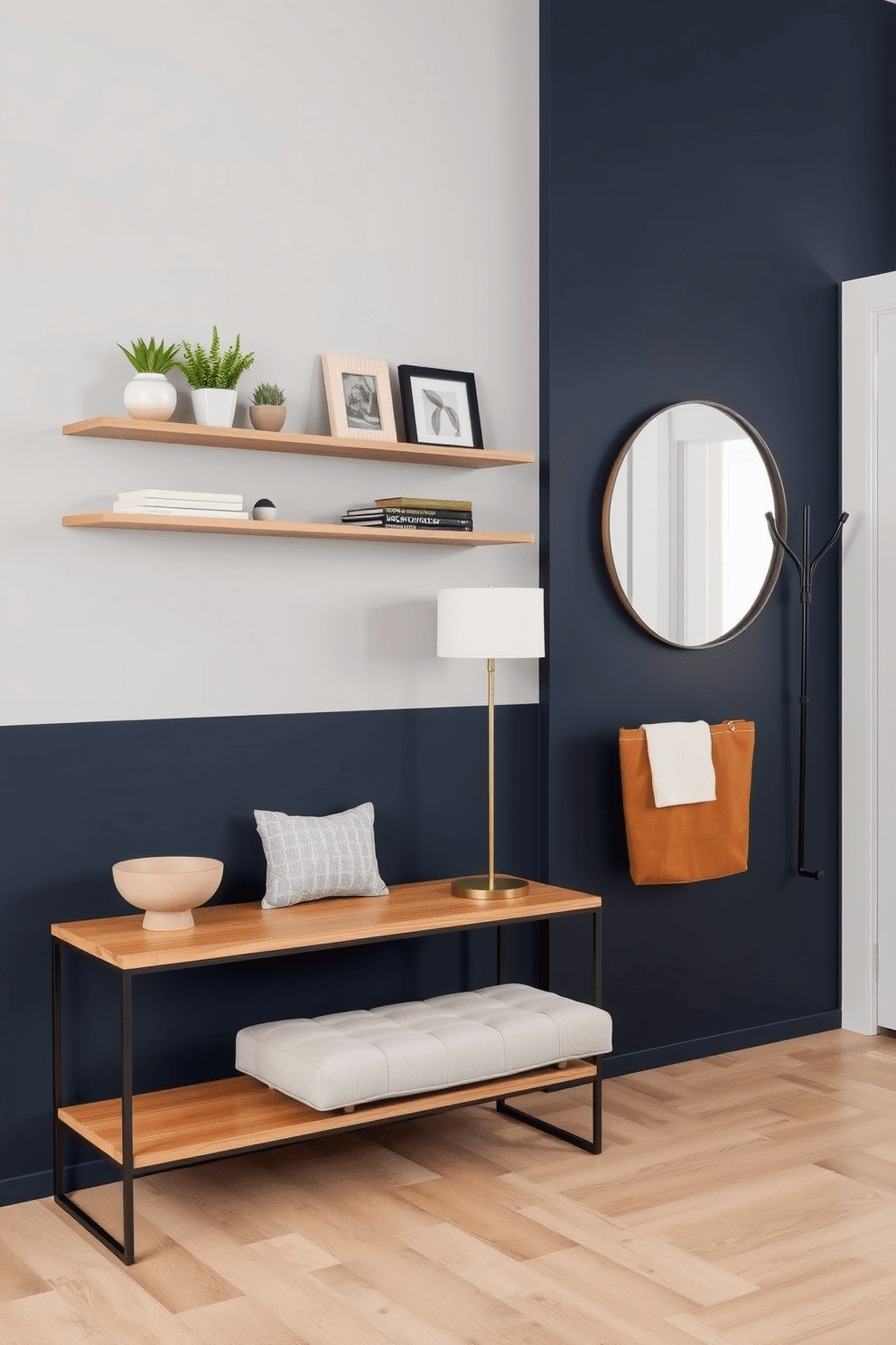 Sleek floating shelves are mounted on a light gray wall, showcasing an array of decorative items such as potted plants, books, and framed photos. Below the shelves, a minimalist console table with a natural wood finish provides additional space for a small decorative bowl and a stylish lamp. The entryway features a bold accent wall painted in deep navy, contrasting with a light wood floor that creates a warm welcome. A modern bench with soft upholstery sits against the wall, accompanied by a chic coat rack and a large round mirror that enhances the sense of space.